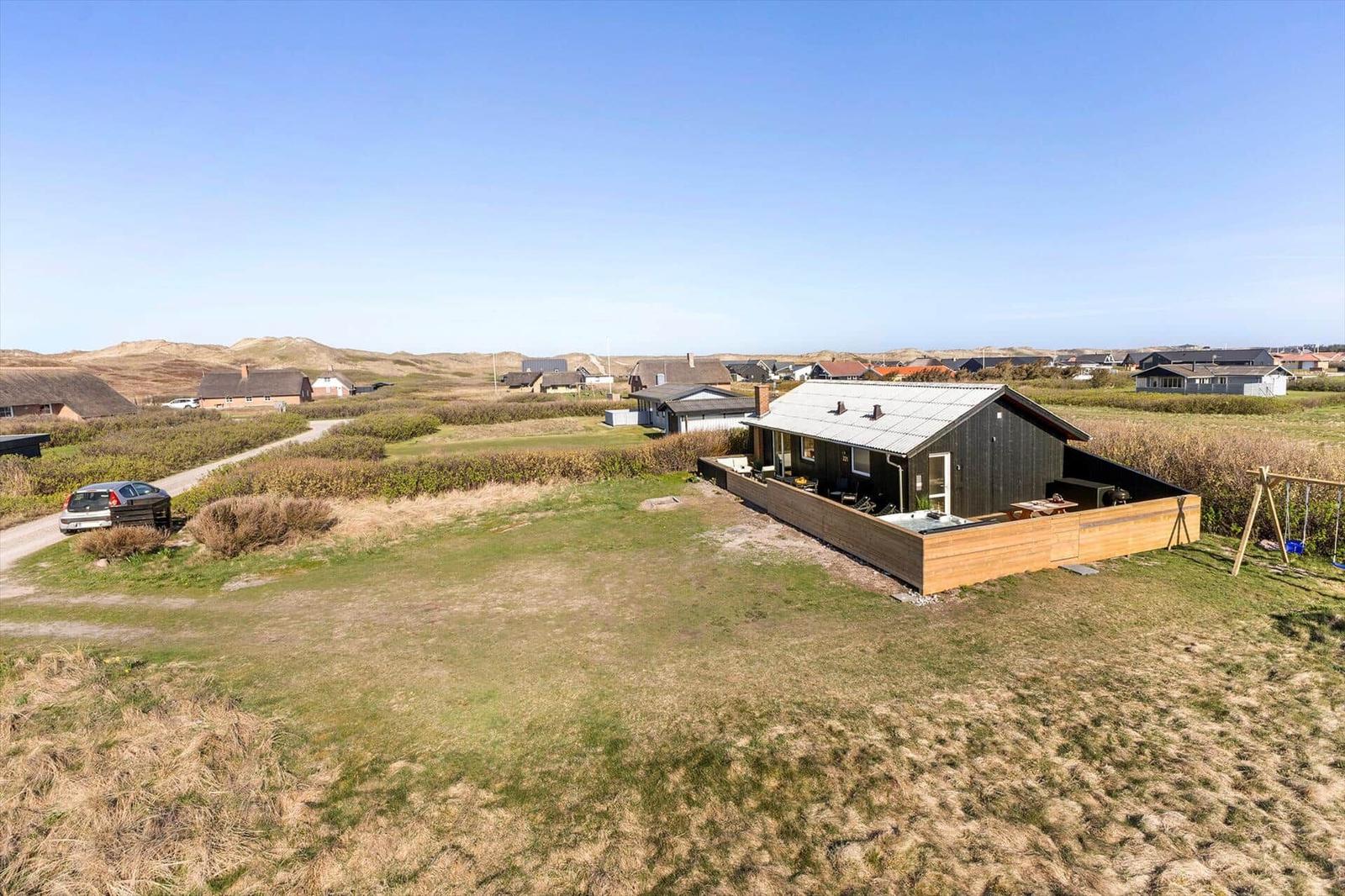 Ein modernes Haus mit Terrasse in einer ländlichen Umgebung mit Gras und Dünen.