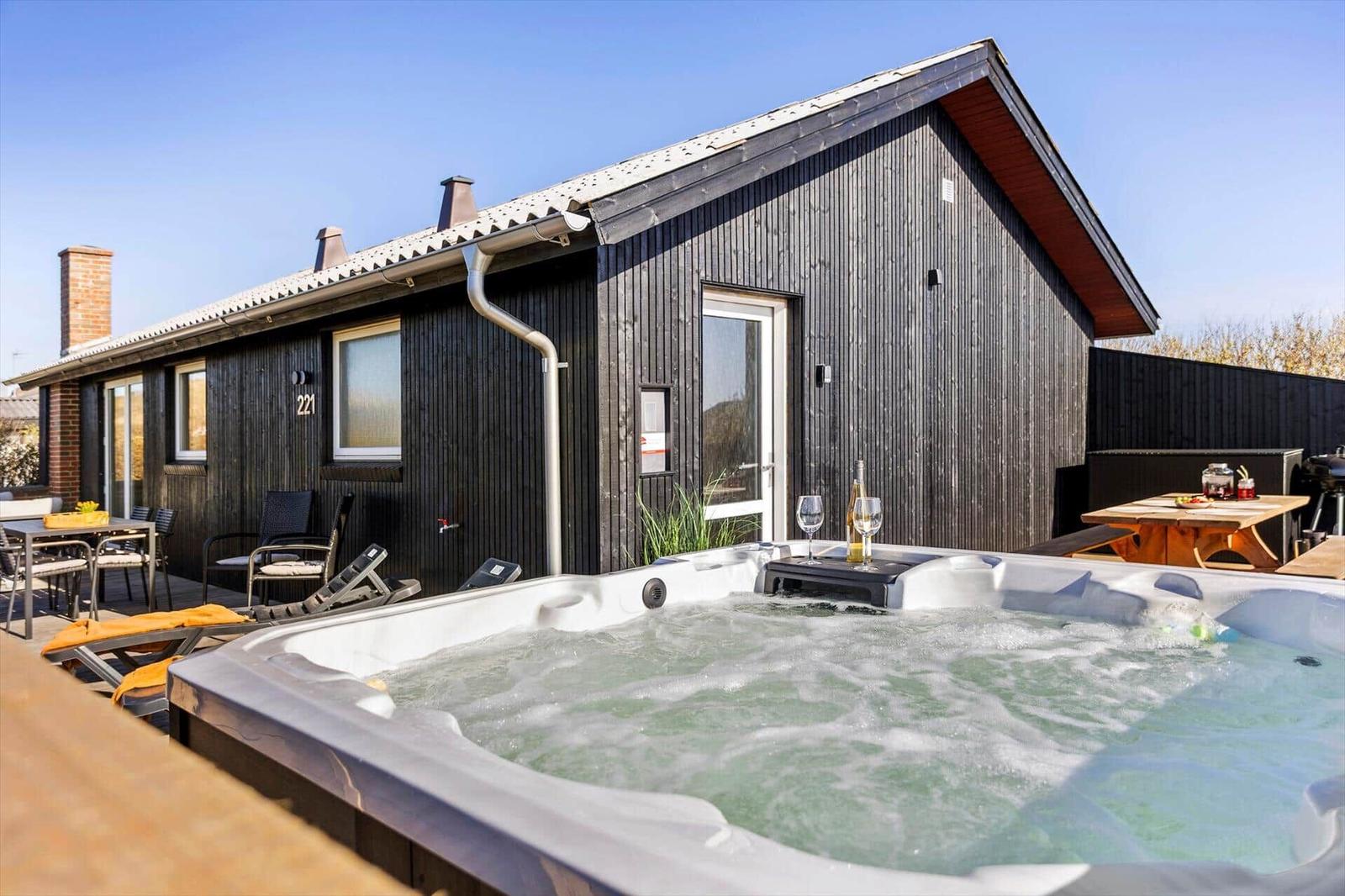Haus mit Whirlpool, Terrasse und Gartenmöbeln im Freien.