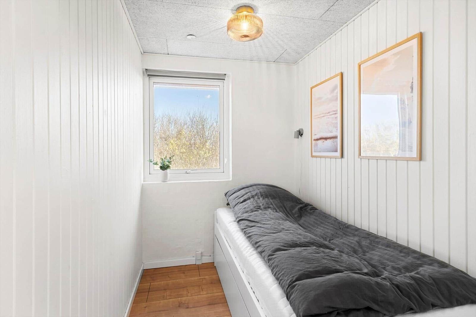 Schlafzimmer mit Bett, Fenster und Wandbildern.