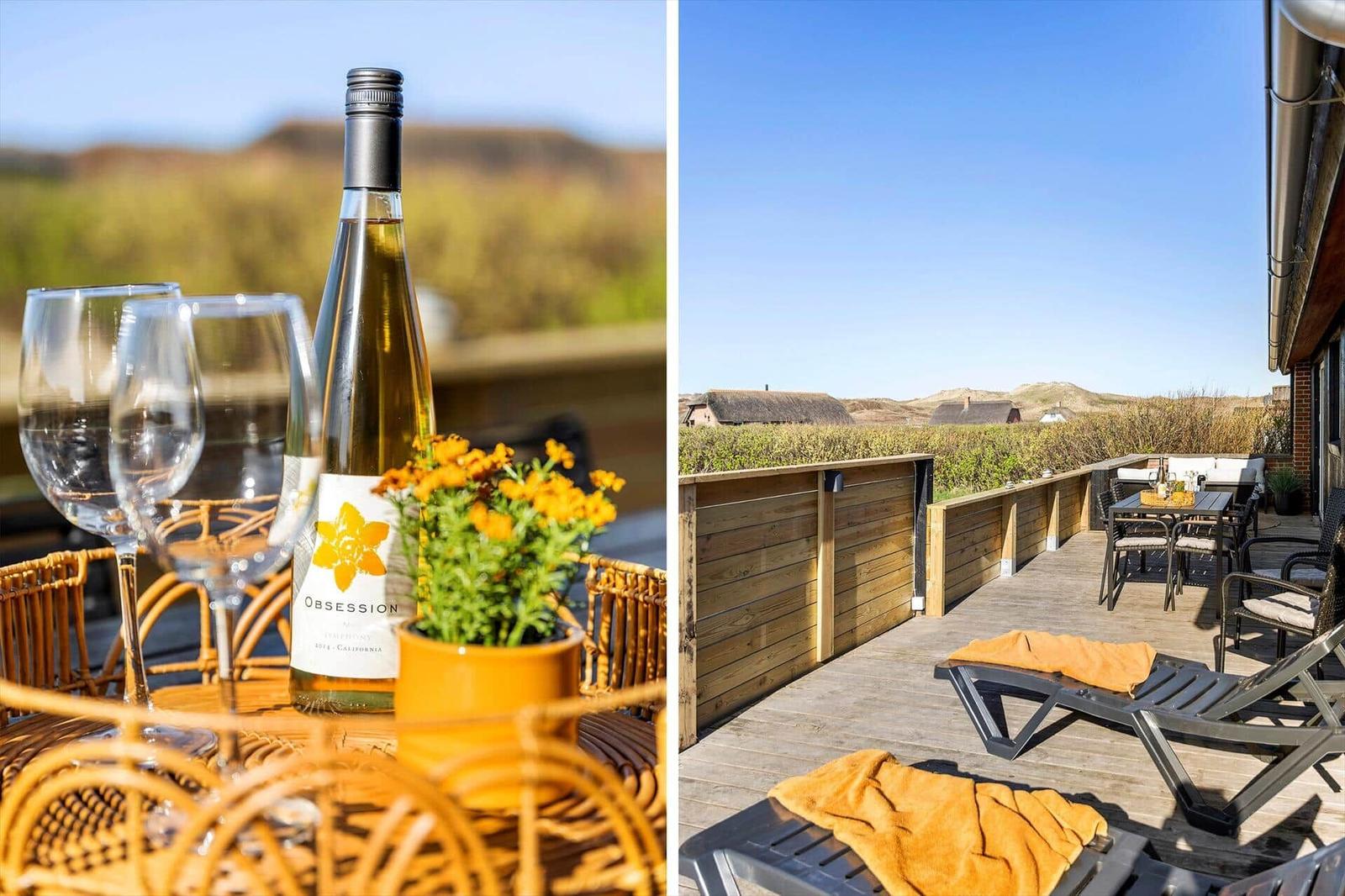 Terrasse mit Liegen und Tisch. Im Hintergrund sind Hügel und Häuser zu sehen.