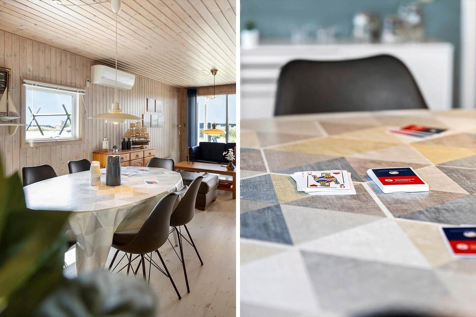 Esszimmer mit runden Tisch und Spielkarten. Holzwand und Fenster sichtbar.