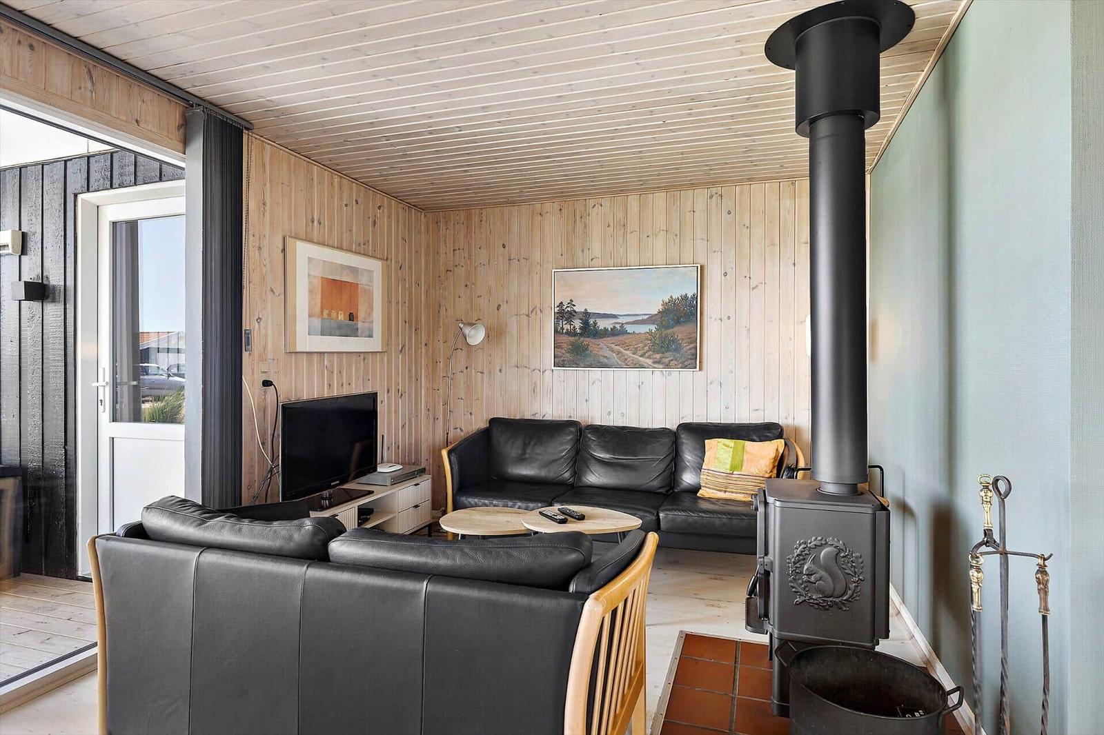 Wohnzimmer mit Ledersofa, Kaminofen und Holzwandverkleidung.