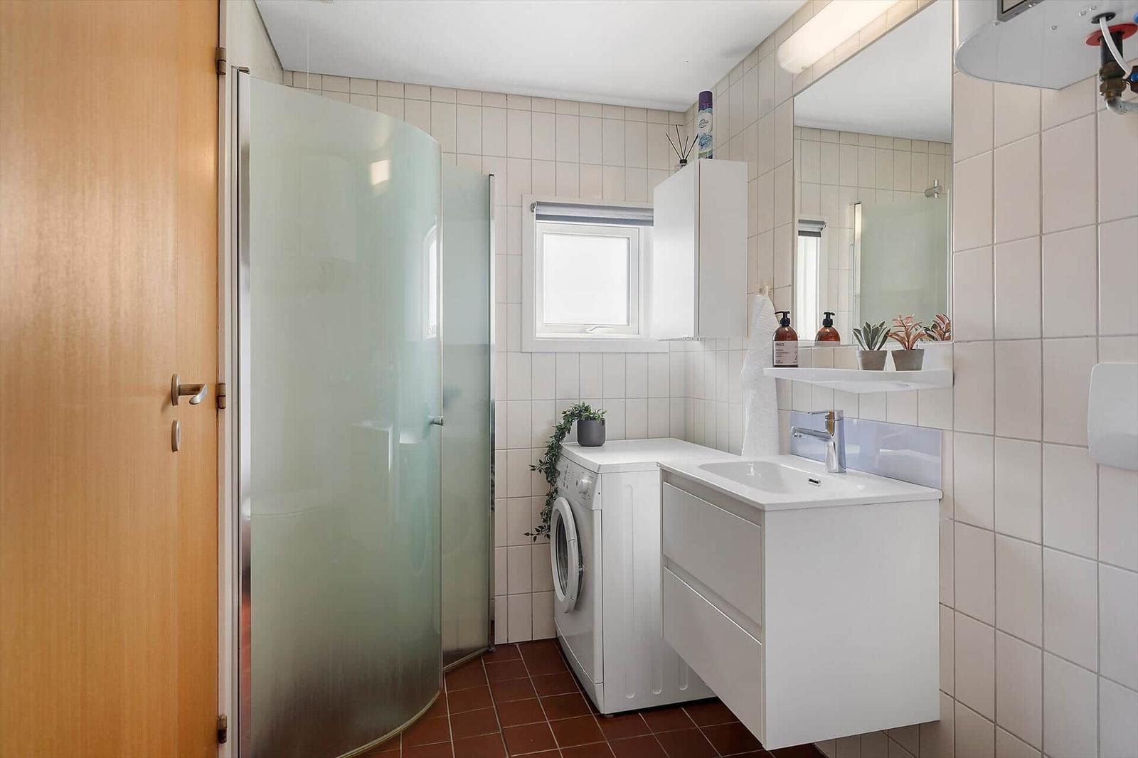Badezimmer mit Dusche, Waschmaschine und Waschtisch