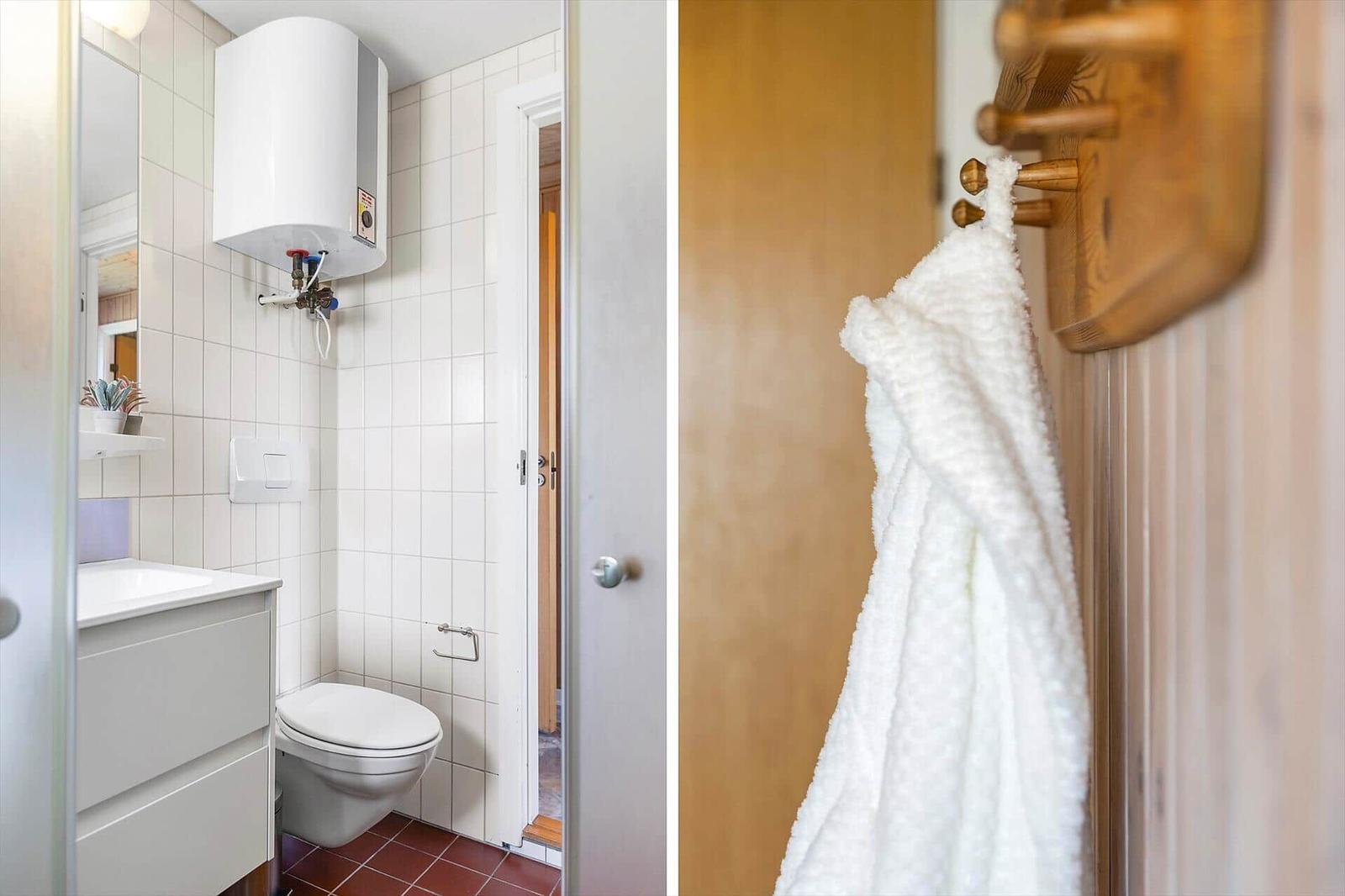 Badezimmer mit Toilette, Waschbecken und Heizung. Weiße Fliesen und brauner Boden. Handtuch an Holzstange.