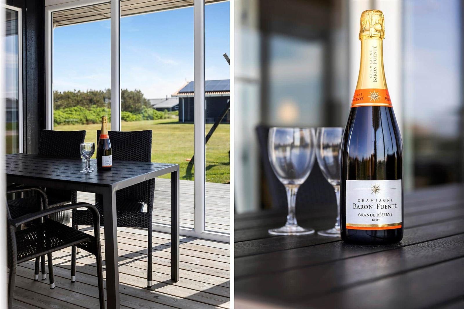 Eine Flasche Champagner und zwei Gläser auf einer Terrasse mit Blick auf einen Garten.