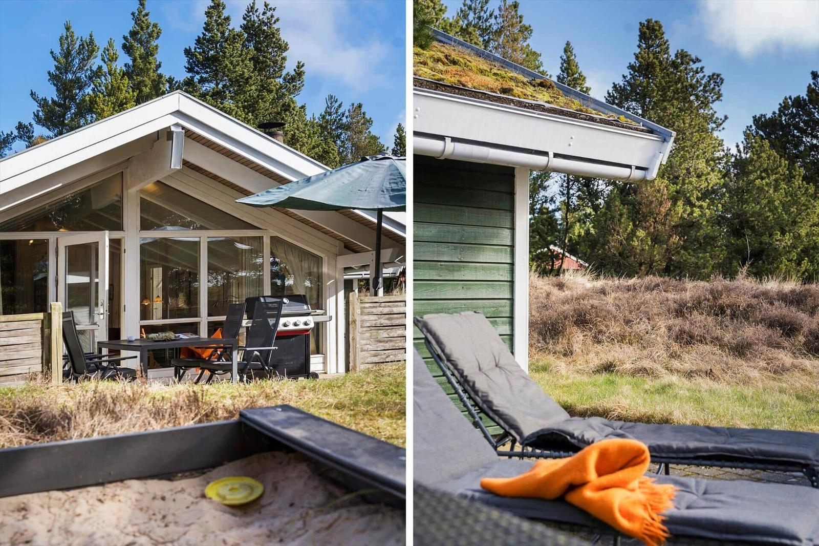 Haus mit Terrasse, Grill und Liegen im Grünen. Dach mit Moos und Holzwände.
