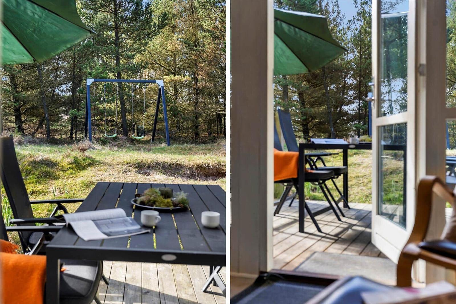 Terrasse mit Tisch, Stühlen und grünem Sonnenschirm. Hintergrund: Wald mit Schaukel.