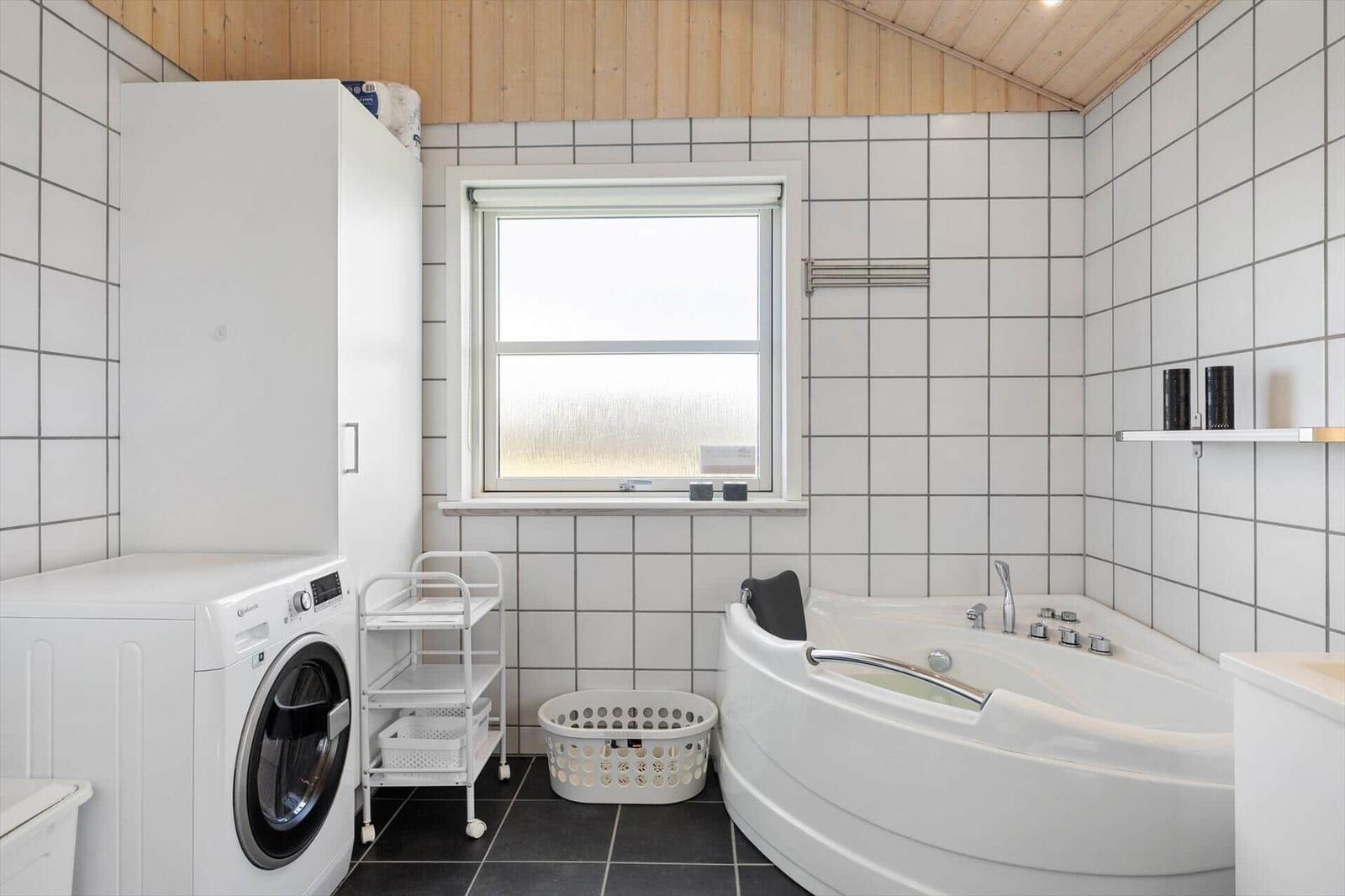 Badezimmer mit Badewanne, Waschmaschine und Fenster