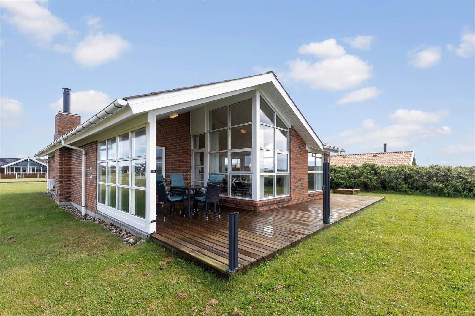 Ein Haus mit Holzterrasse und großen Fenstern im Freien.