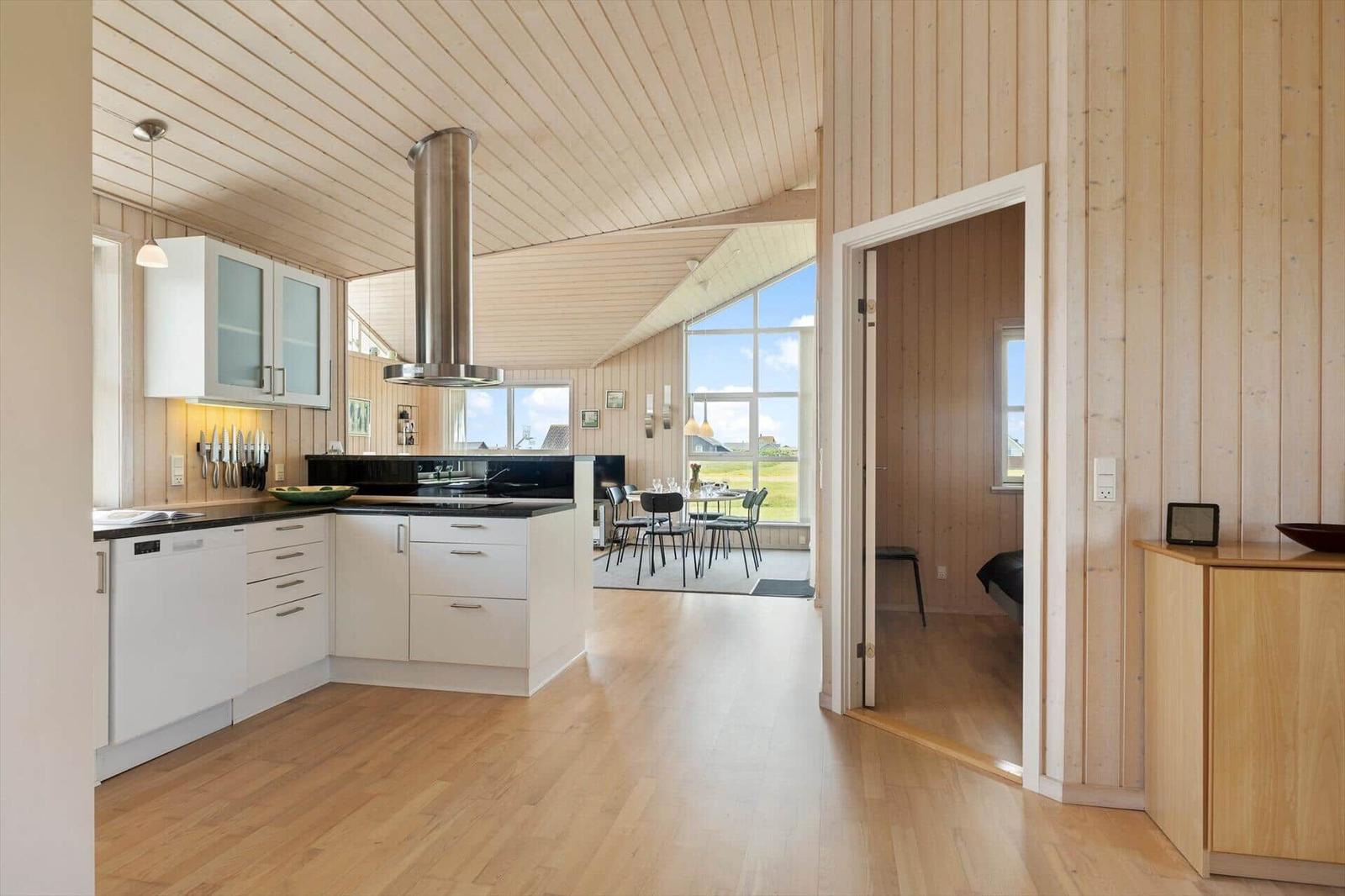 Küche mit Essbereich und Schlafzimmer. Holzvertäfelung und große Fenster.
