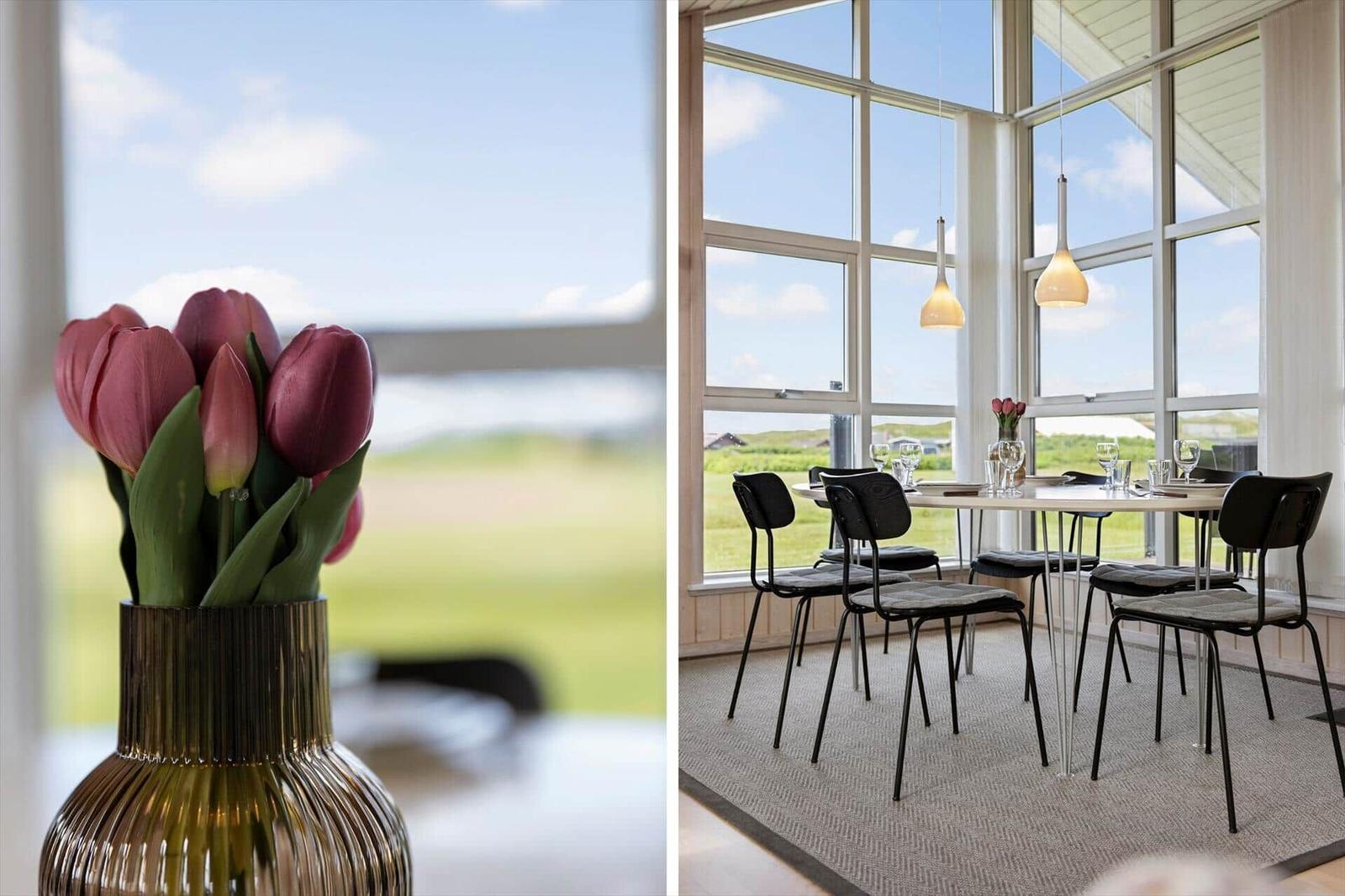 Esszimmer mit großem Fenster, Tisch und Stühlen, Tulpen im Vordergrund.