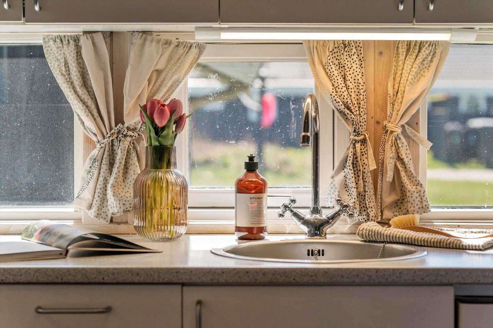 Küchenfenster mit Vorhängen, Blumen, Spüle und Seife