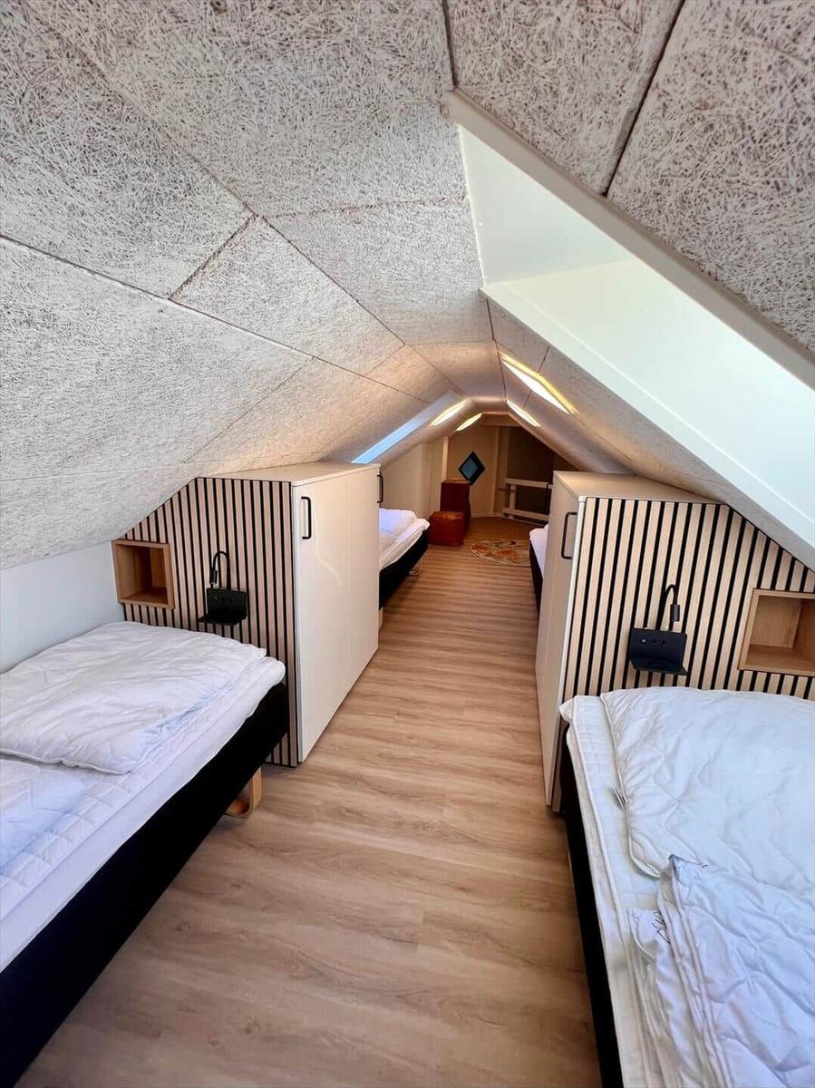 Schlafzimmer mit zwei Betten unter Dachschrägen und Holzboden