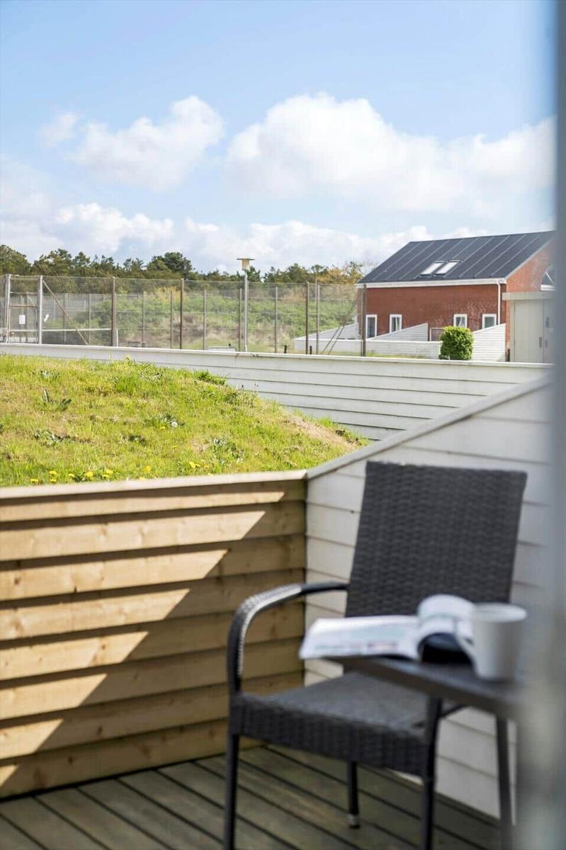 Terrasse mit Stuhl und Tisch. Grasfläche und Haus im Hintergrund.