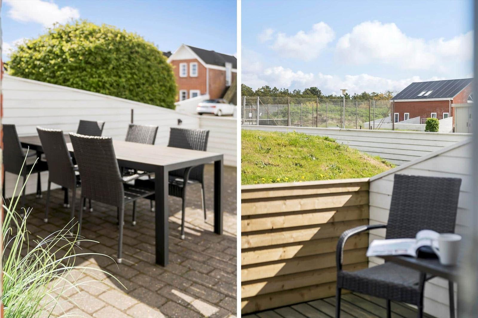 Terrasse mit Tisch und Stühlen. Blick auf grünen Hang und Nachbarhaus.
