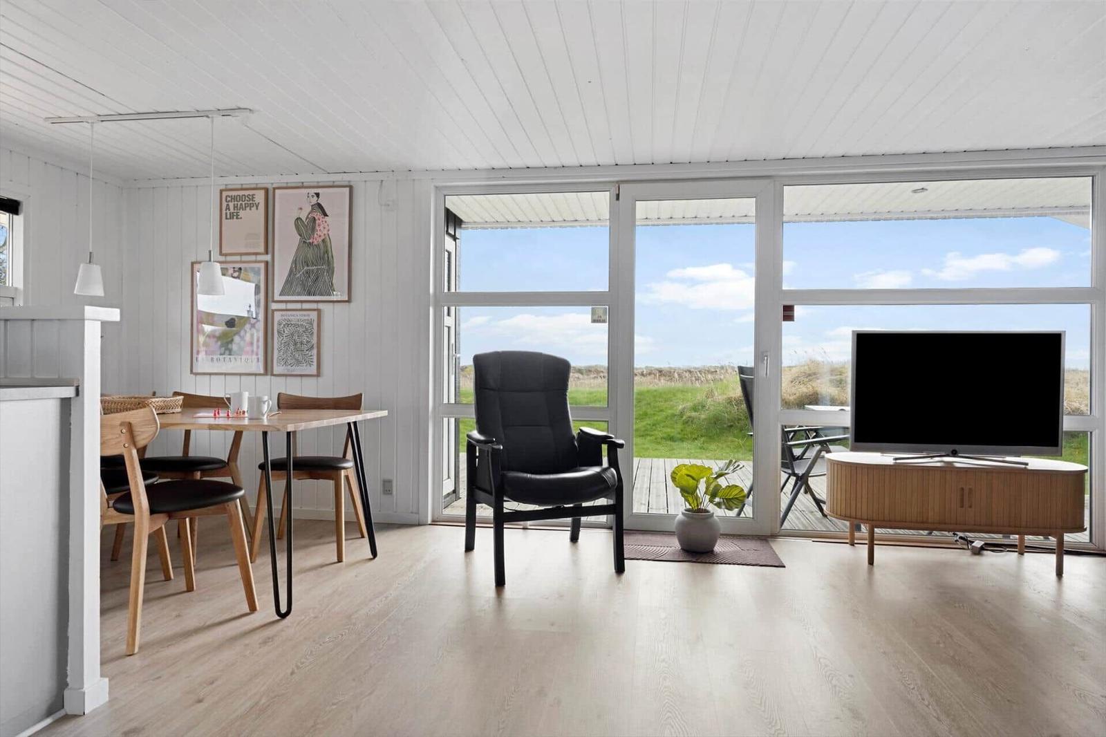 Wohnzimmer mit Essbereich, großes Fenster und Sicht auf Grasland.