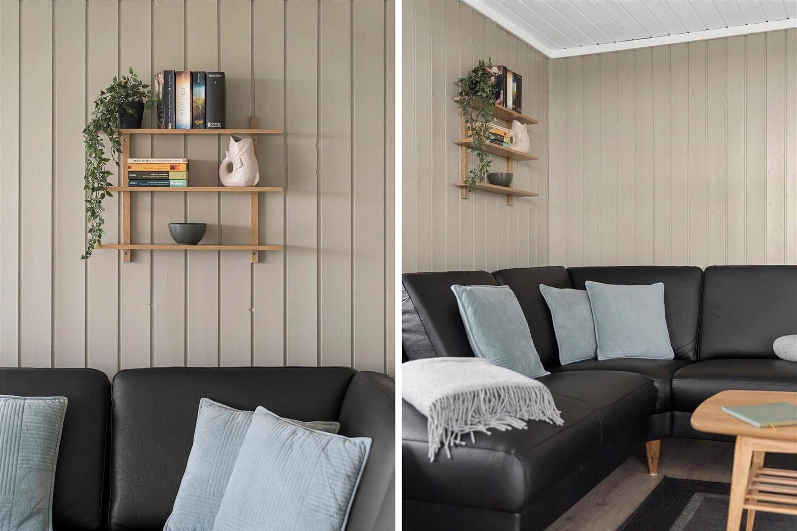 Schwarzes Sofa mit hellblauen Kissen und Holzregal an der Wand.
