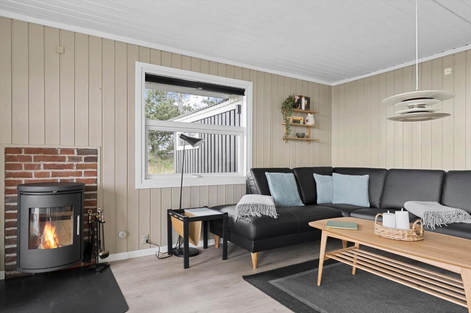 Wohnzimmer mit Sofa, Kamin und Fensterblick.