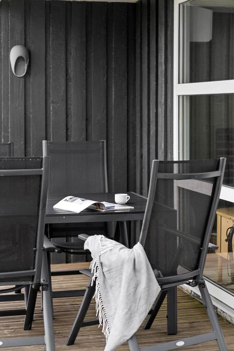 Terrasse mit Tisch und Stühlen, weiße Tasse und Zeitschrift auf Tisch