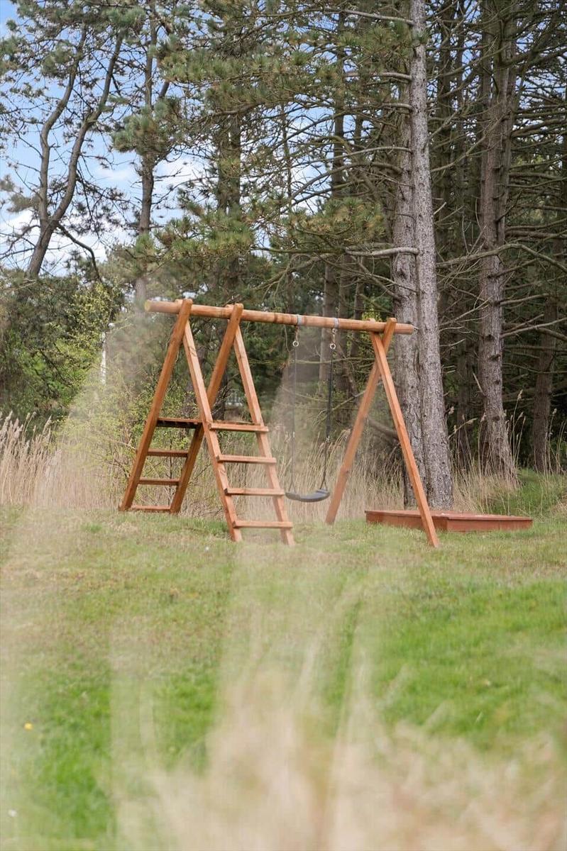 Holzschaukel mit Leiter im Waldgebiet auf Grasfläche