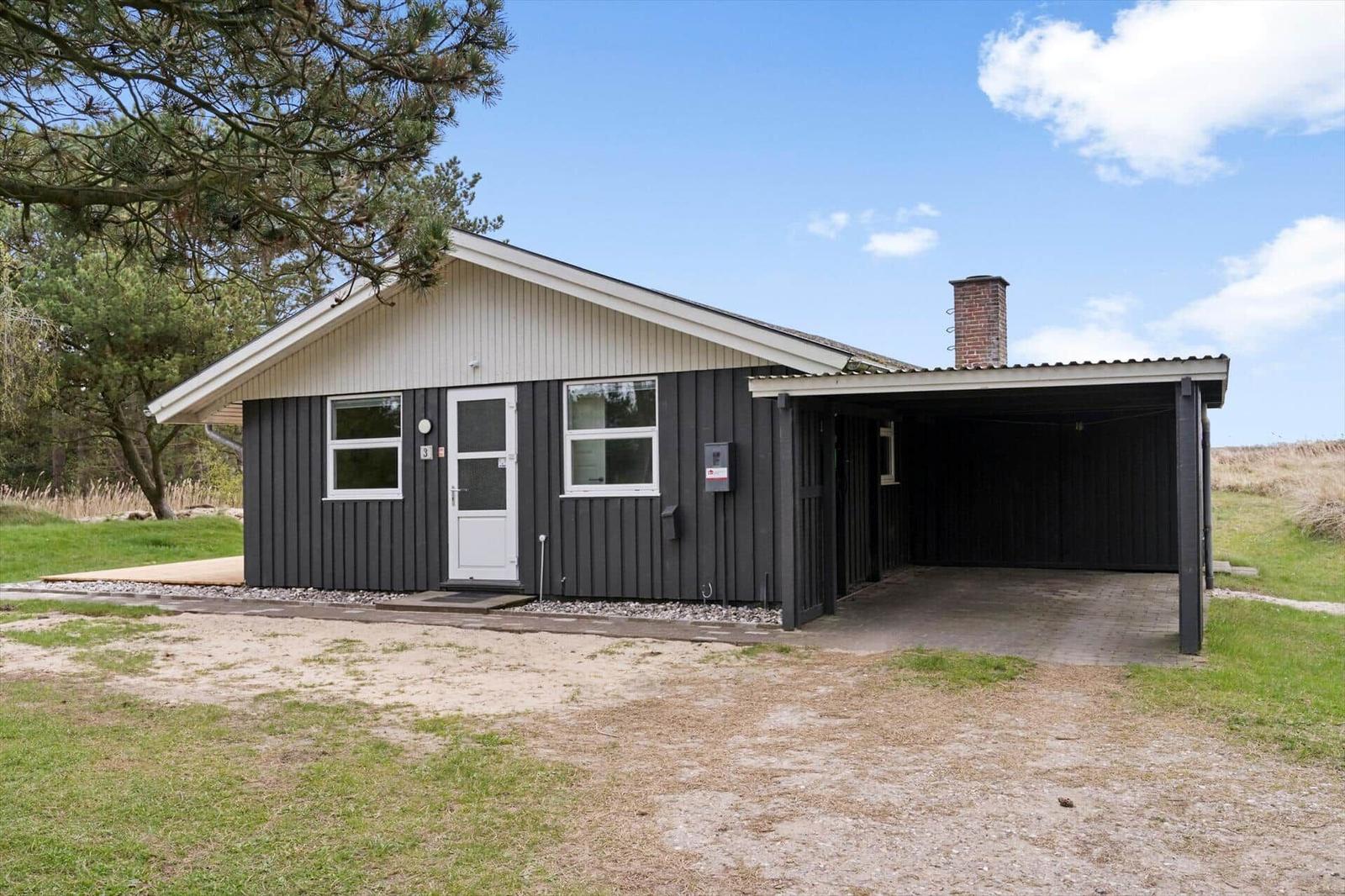 Einhaus mit Garage, weißer Tür und Schornstein unter blauem Himmel.