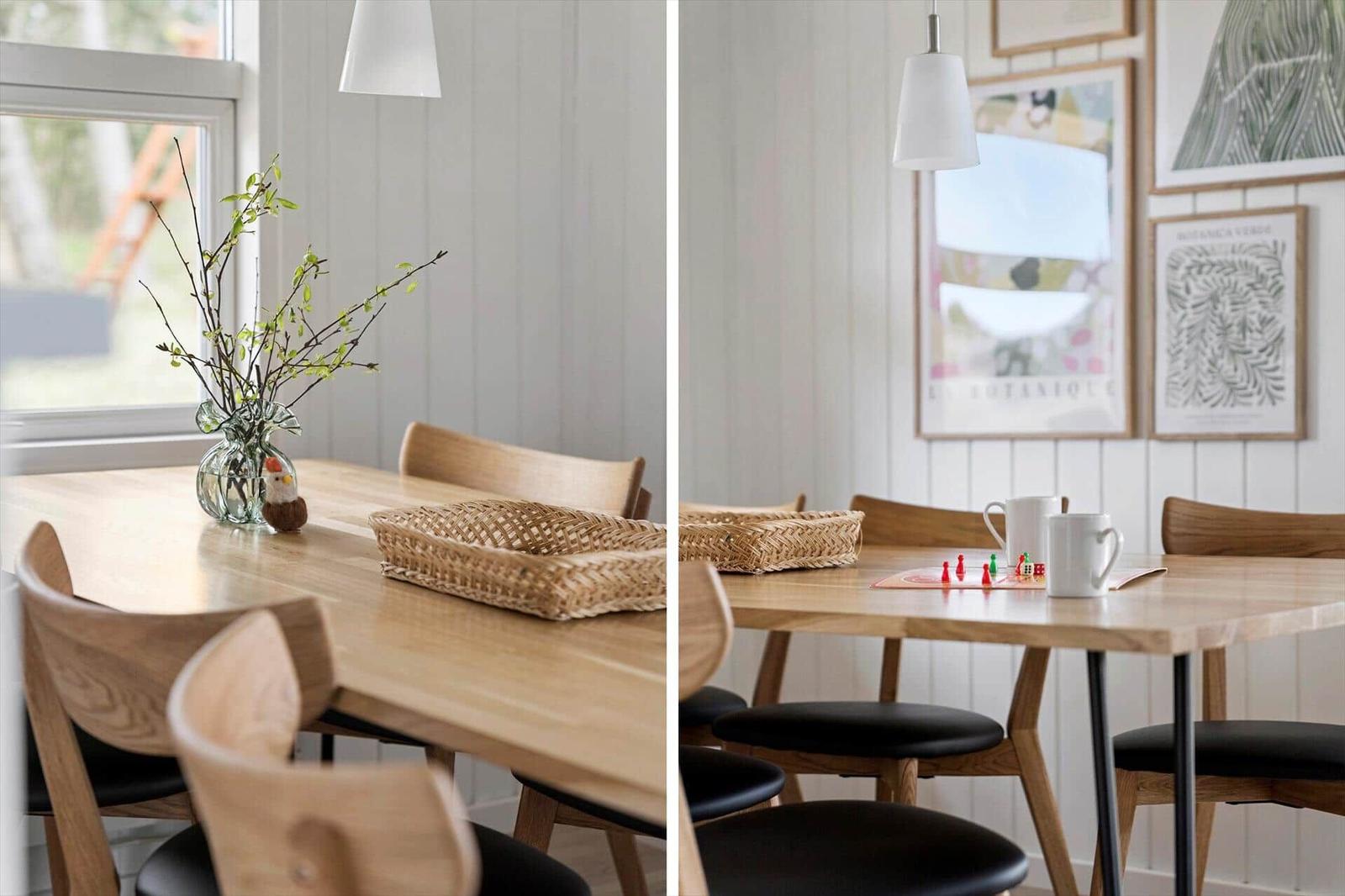 Holztisch mit Stühlen, Blumen und Körben. Wand mit Bildern und Hängelampe.