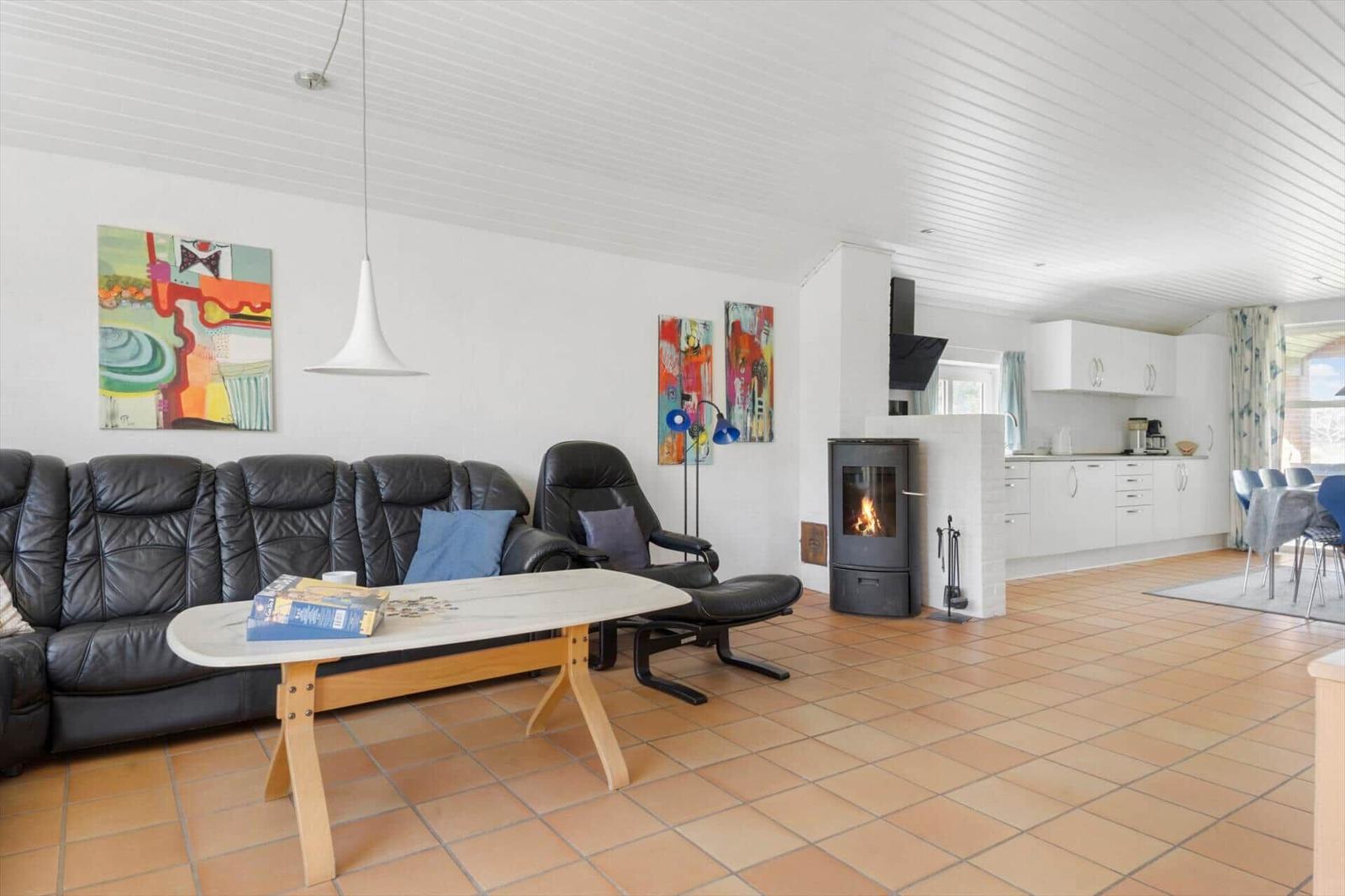 Wohnzimmer mit Sofa, Kamin und offener Küche