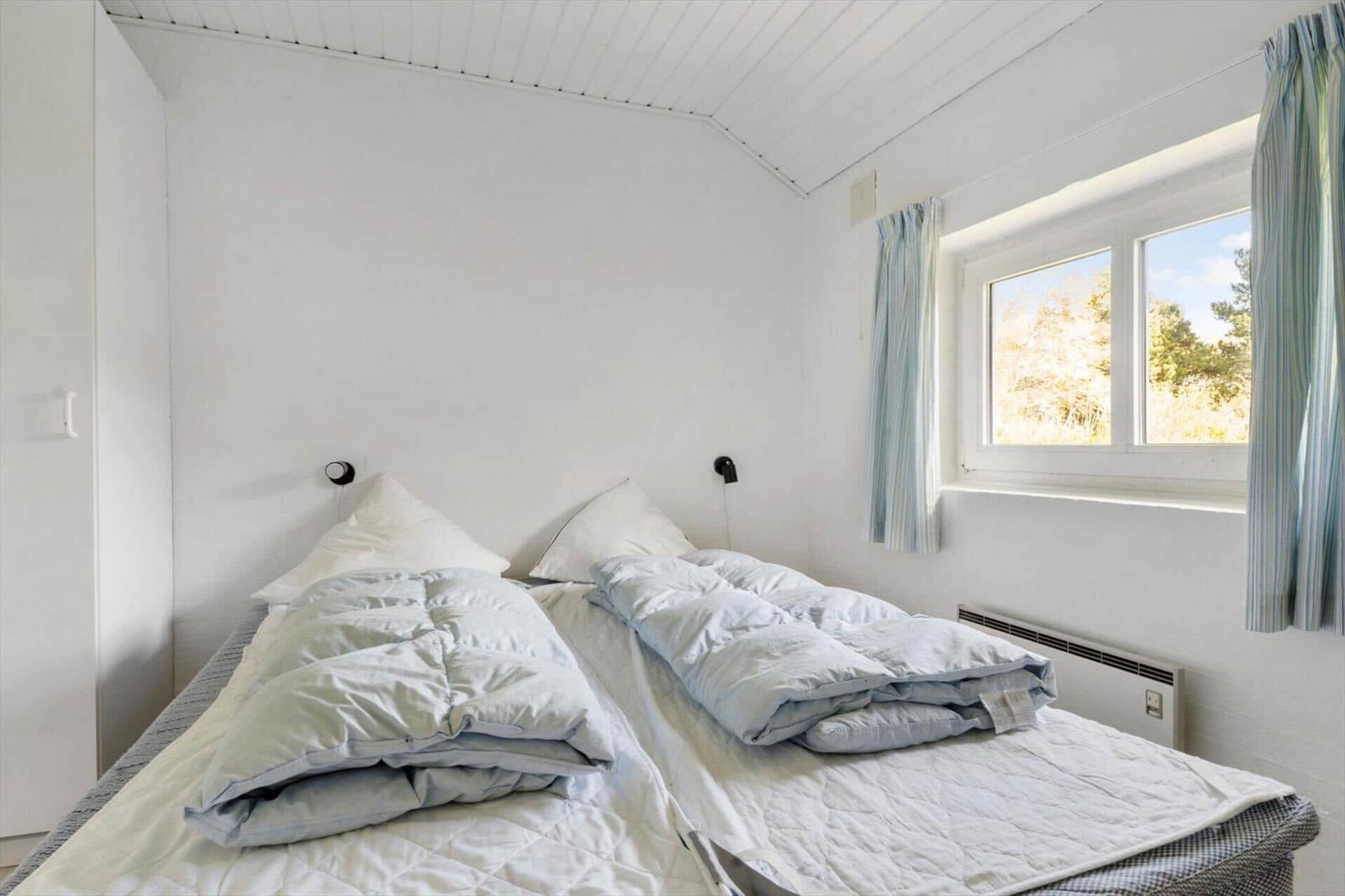 Schlafzimmer mit Doppelbett, Fenster und Heizung.
