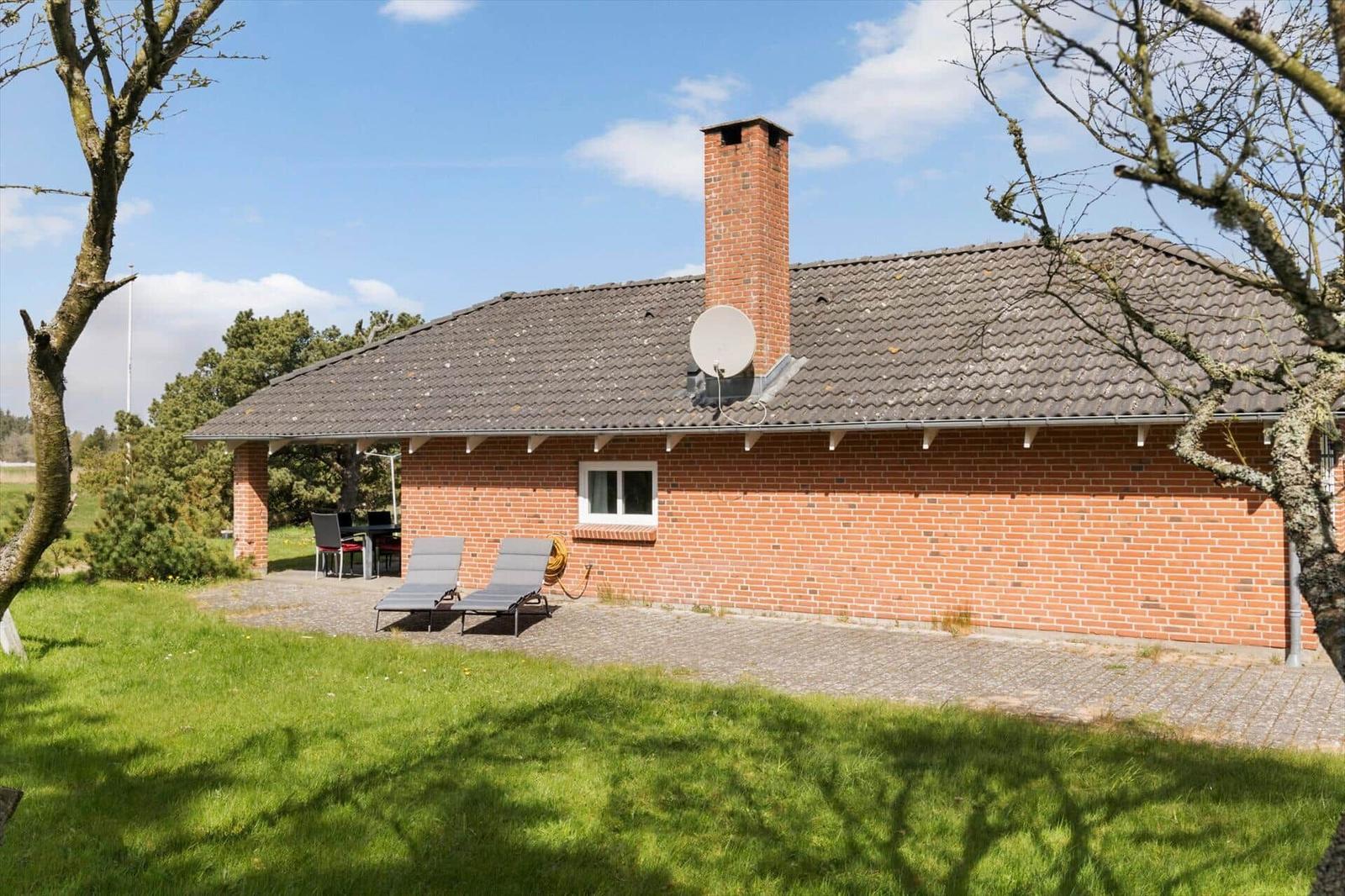 Rotes Backsteinhaus mit Dachterrasse, Sonnenliegen und Satellitenschüssel.
