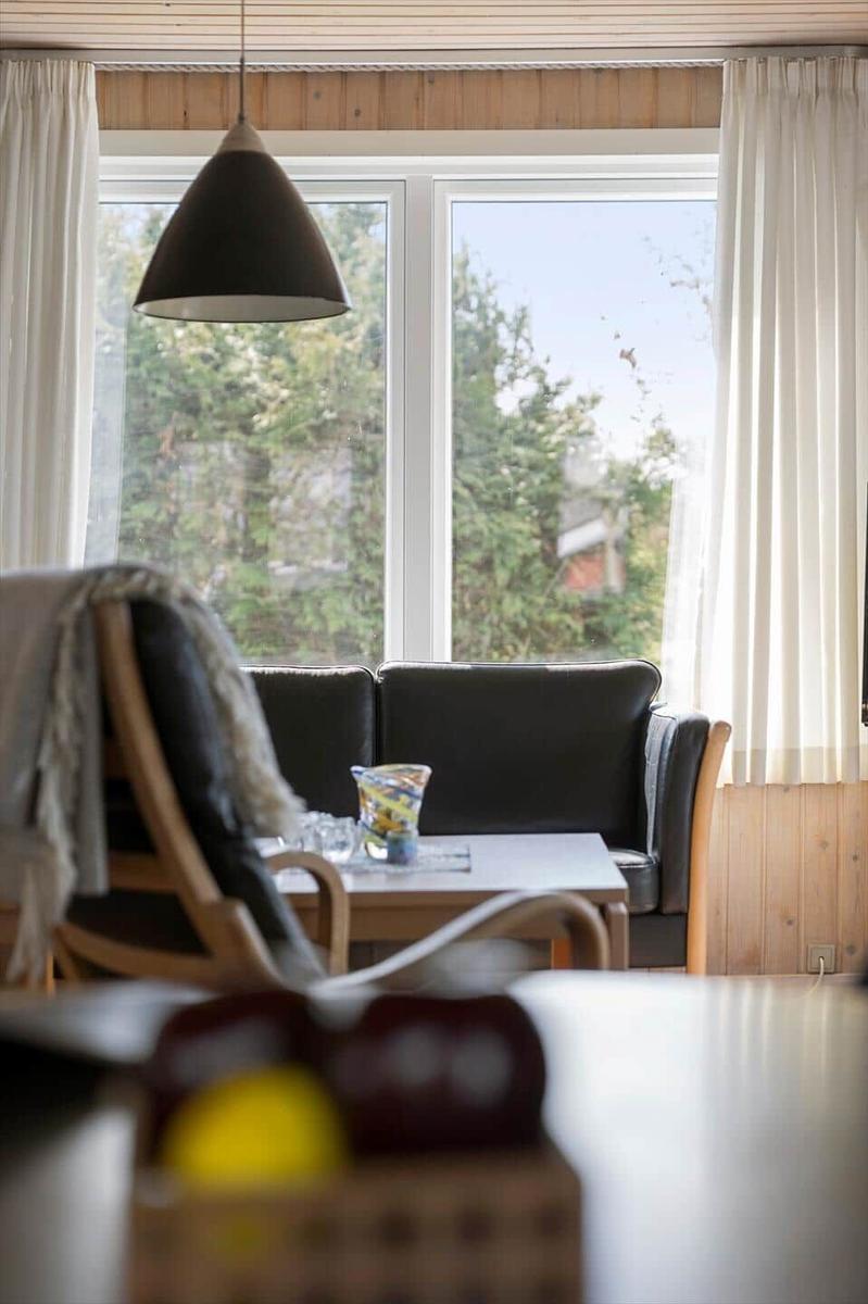 Ein Raum mit einem Sofa, Tisch und Fenster. Vor dem Fenster sind Bäume sichtbar.
