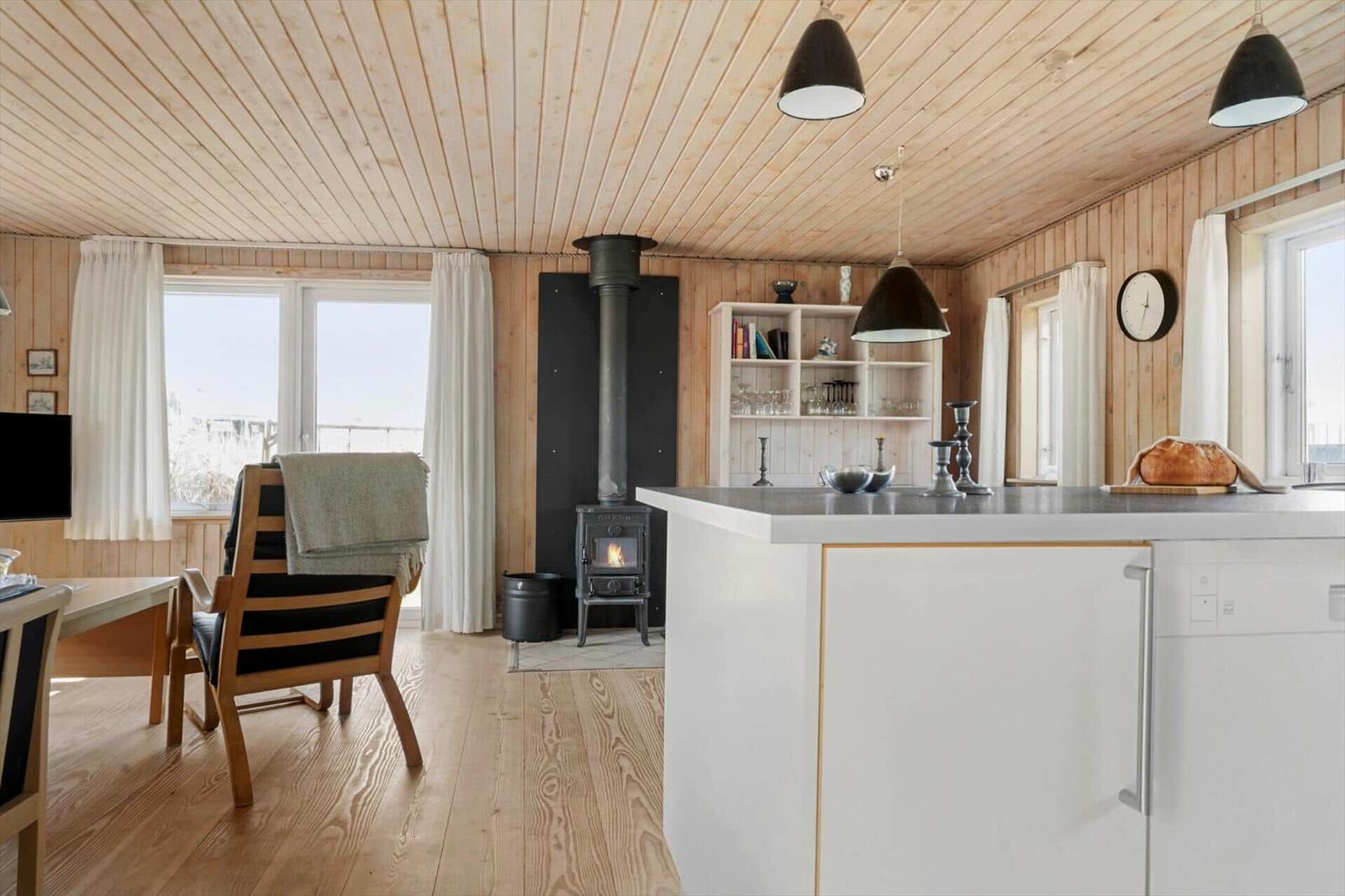 Küche mit Essbereich, Holzdecke, Kamin und Fenster mit Blick.