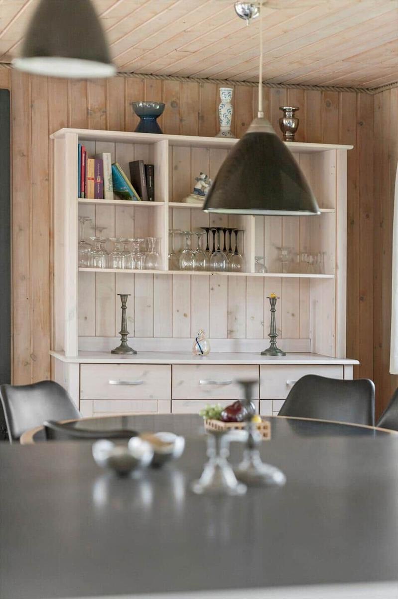 Esstisch mit Stühlen und Sideboard mit Gläsern und Büchern.