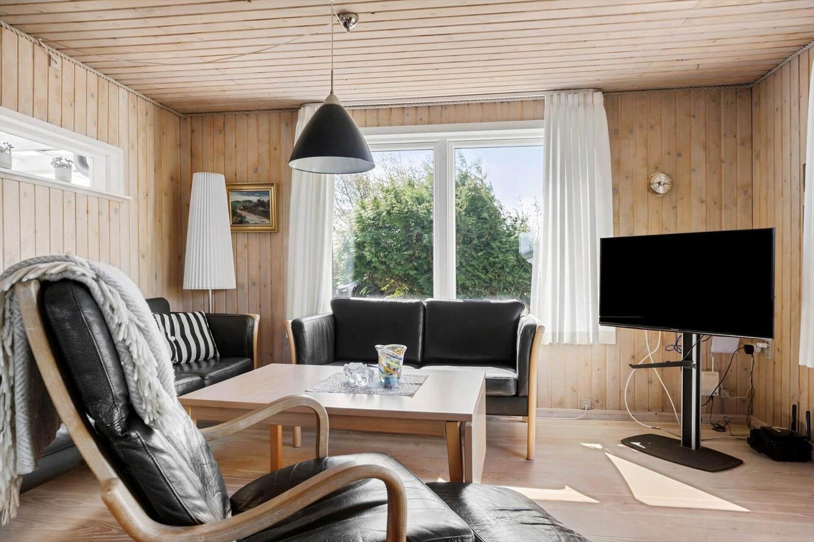 Wohnzimmer mit Holzwand, Sofa, Fernseher und Tisch.