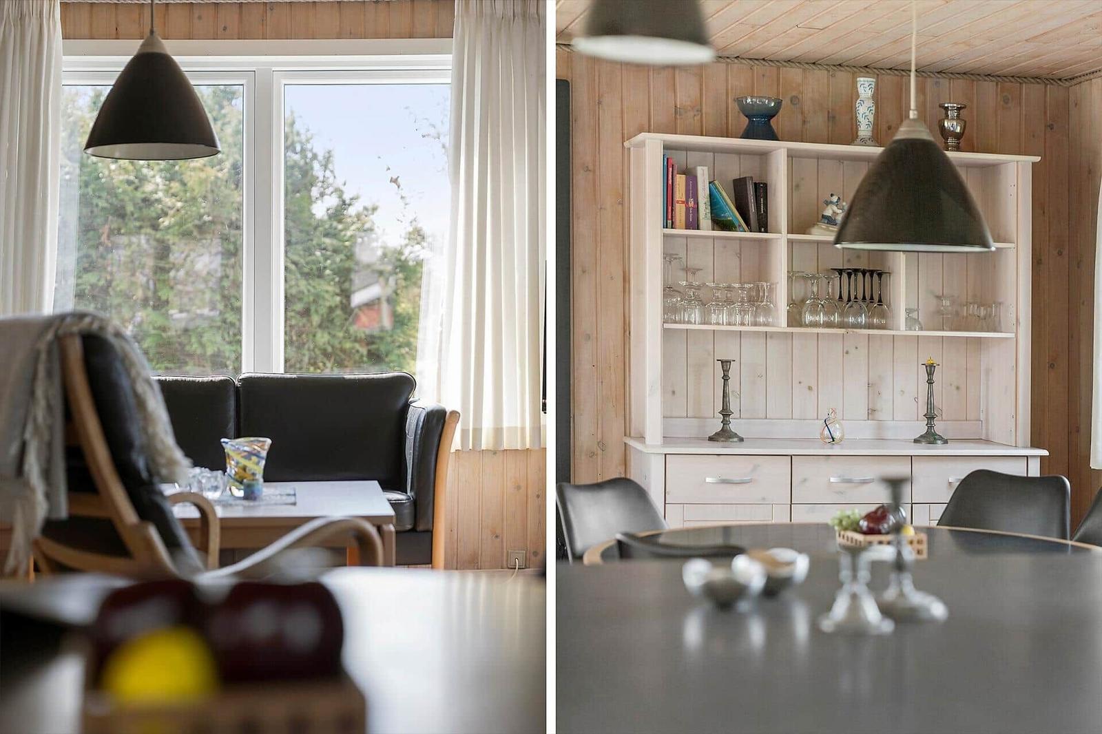 Wohn- und Essbereich mit Holzwänden, Fenster und Schrank. Tische, Stühle und Lampen sichtbar.