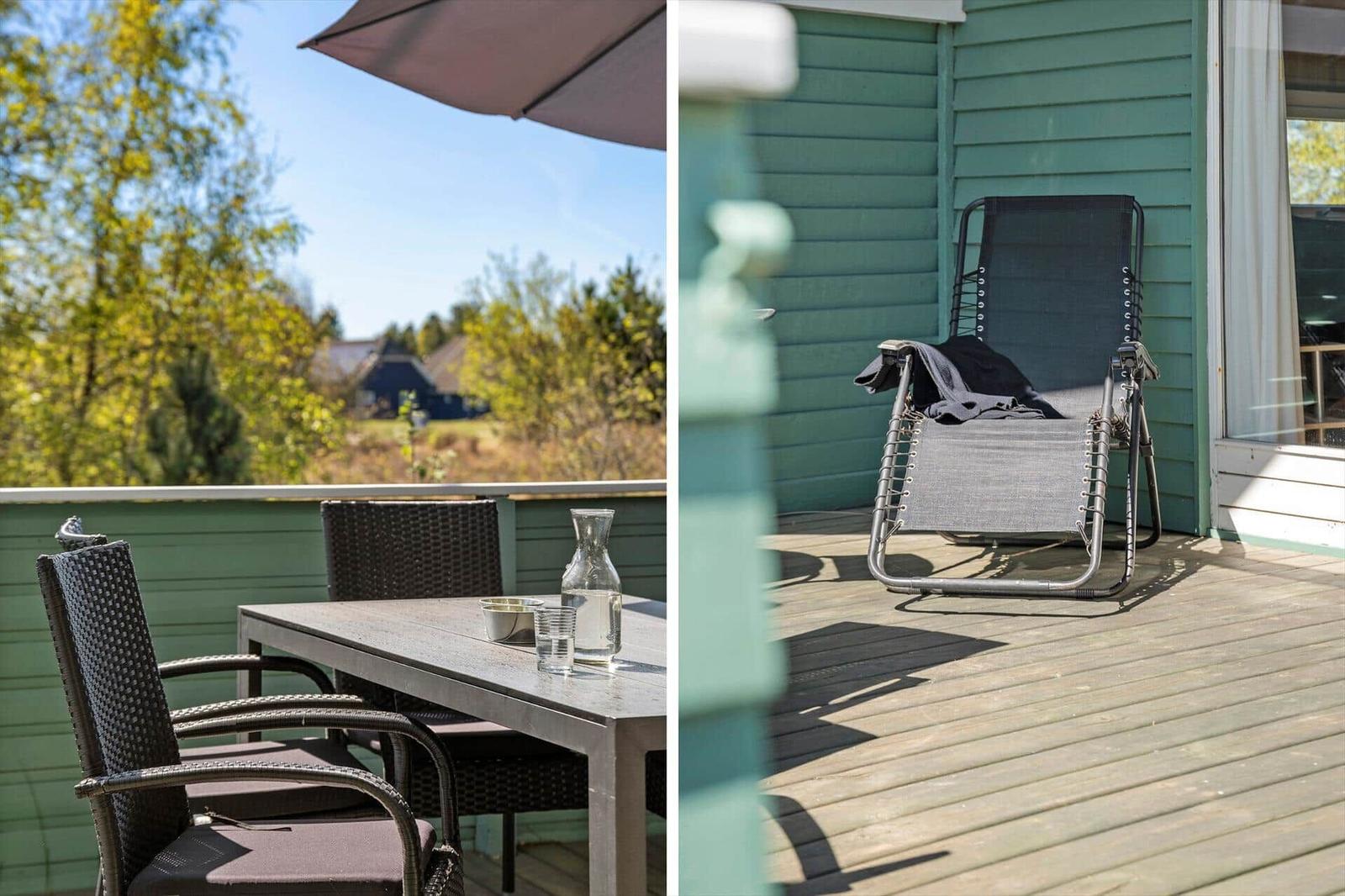 Terrasse mit Tisch, Stühlen und Sonnenschutz. Rechts: Liegestuhl an Hauswand.