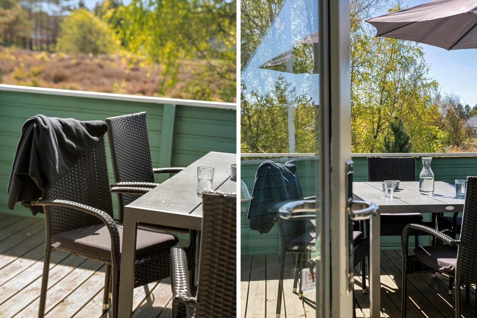 Terrasse mit Tisch und Stühlen, Blick auf grüne Bäume und Heide.
