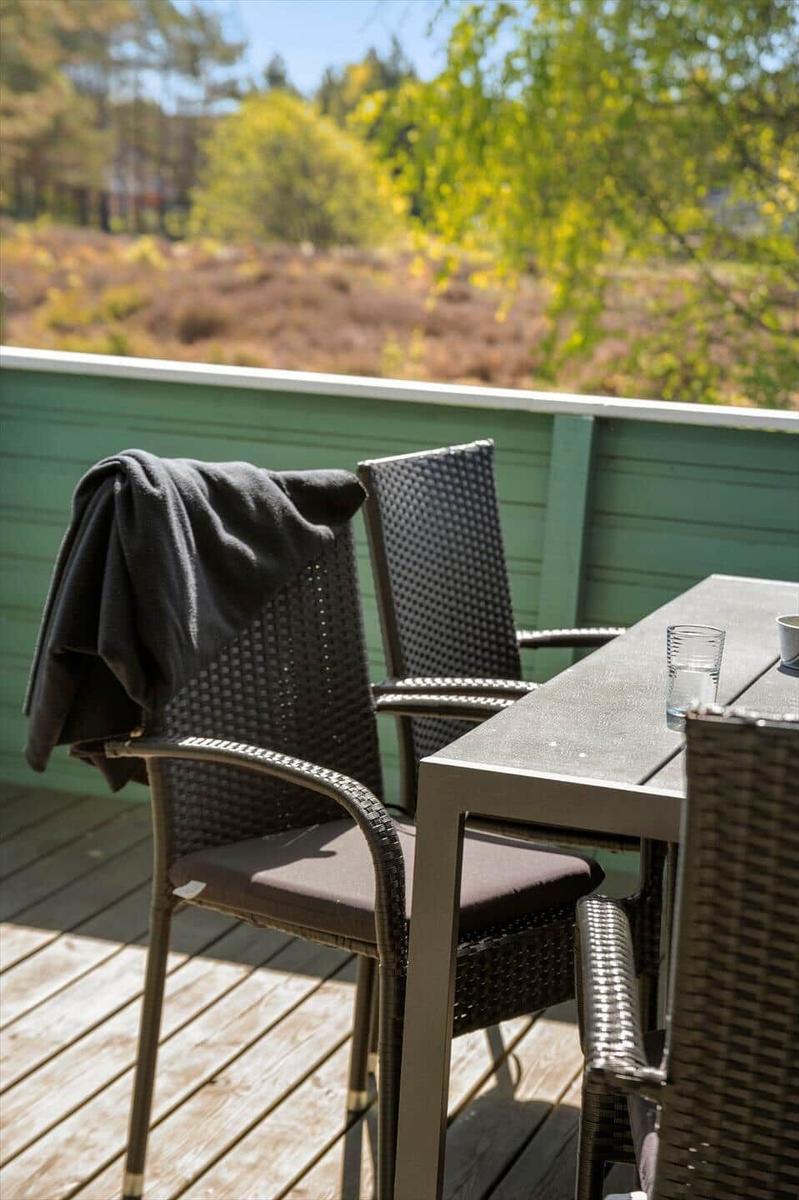 Terrasse mit Tisch und Stühlen. Hintergrund: Wald und Grünflächen.