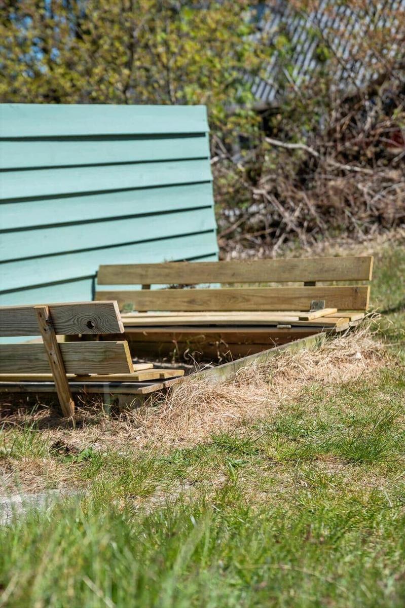 Holzbank vor hellblauem Holzhaus im Garten