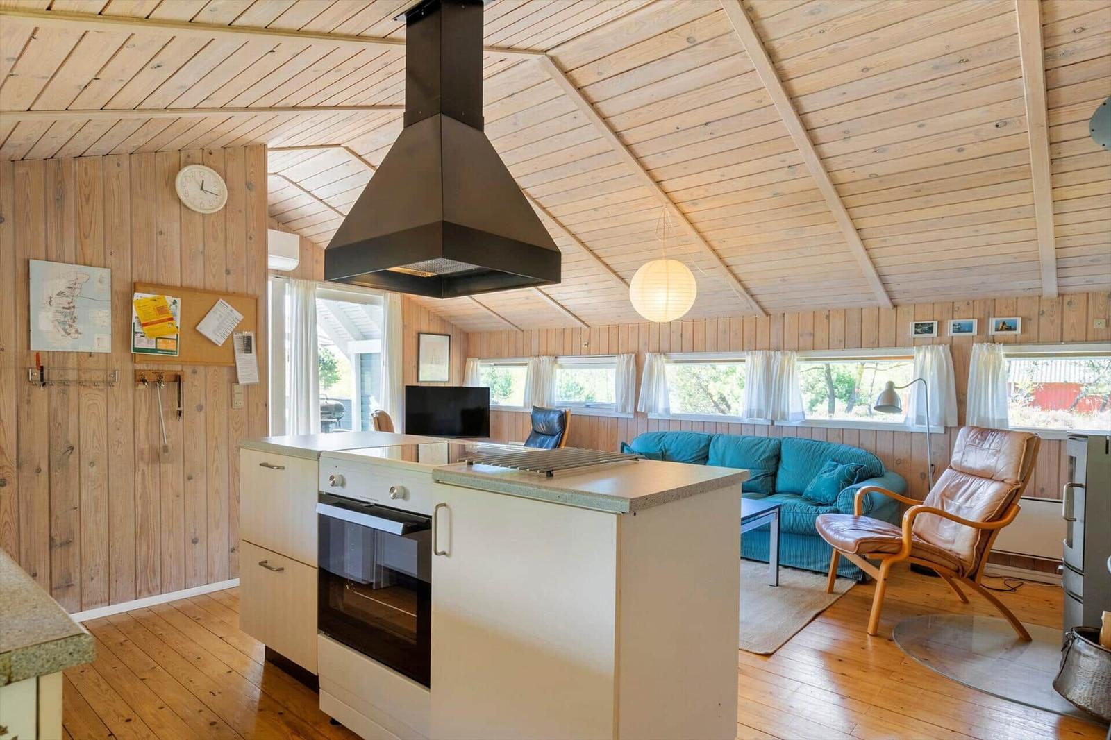 Küche mit Insel und Wohnbereich mit Sofa und Sessel.