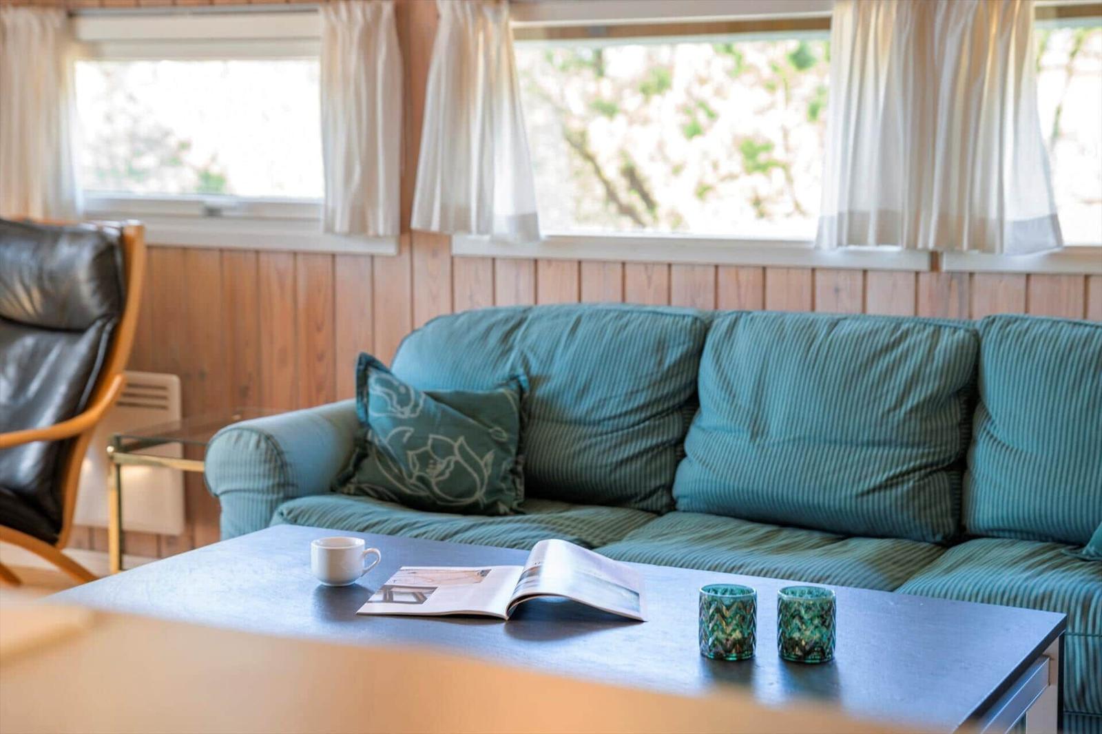 Ein Wohnzimmer mit Sofa, Couchtisch und Fenstern mit Vorhängen.