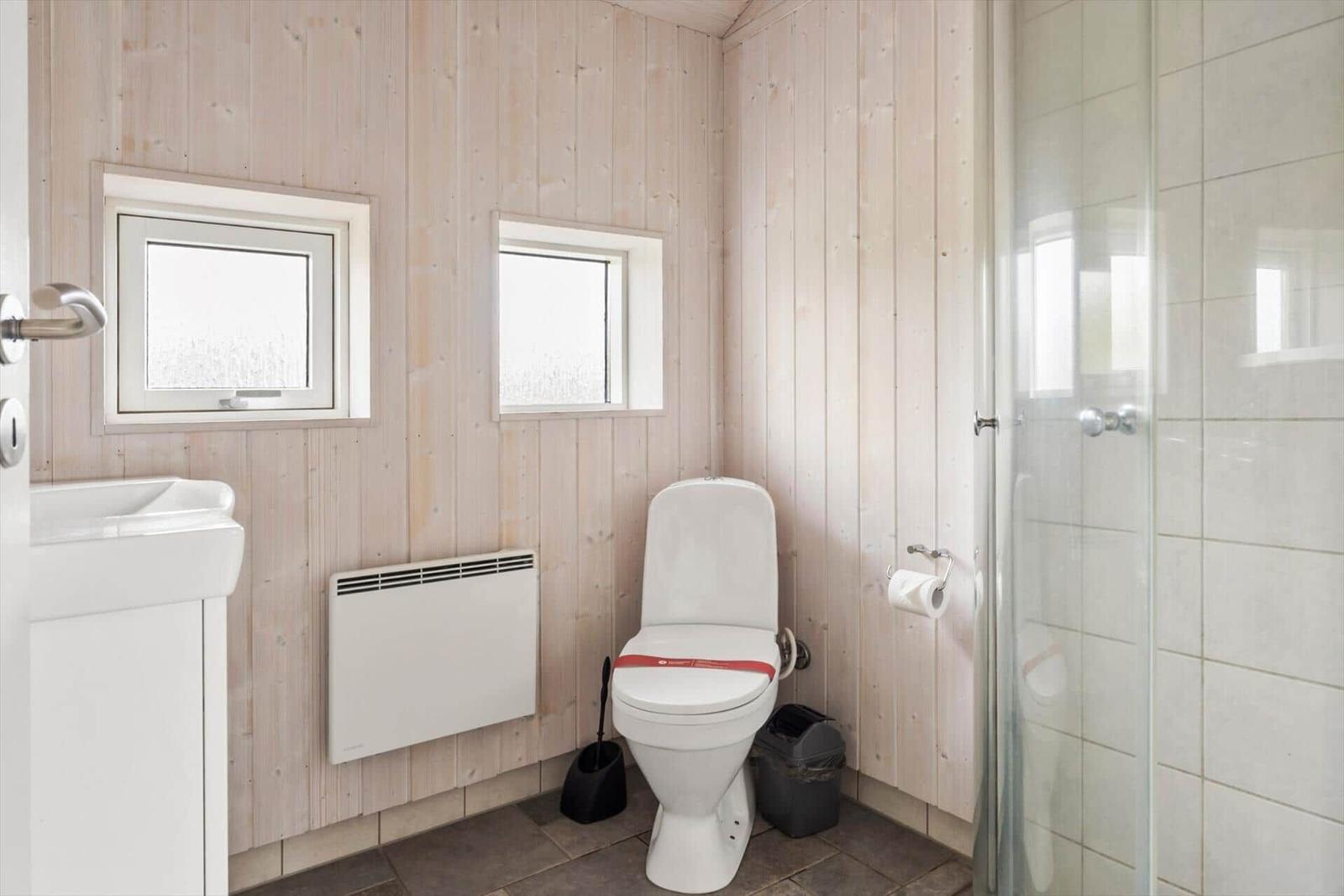 Badezimmer mit Toilette, Dusche und Waschbecken an Holzwand