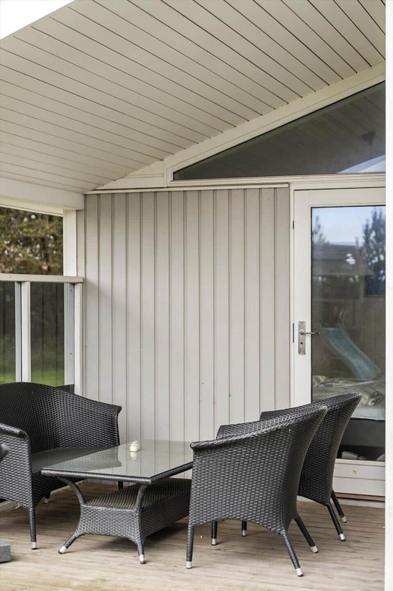 Terrasse mit Wicker-Sitzgruppe und Glas-Tisch unter Dach