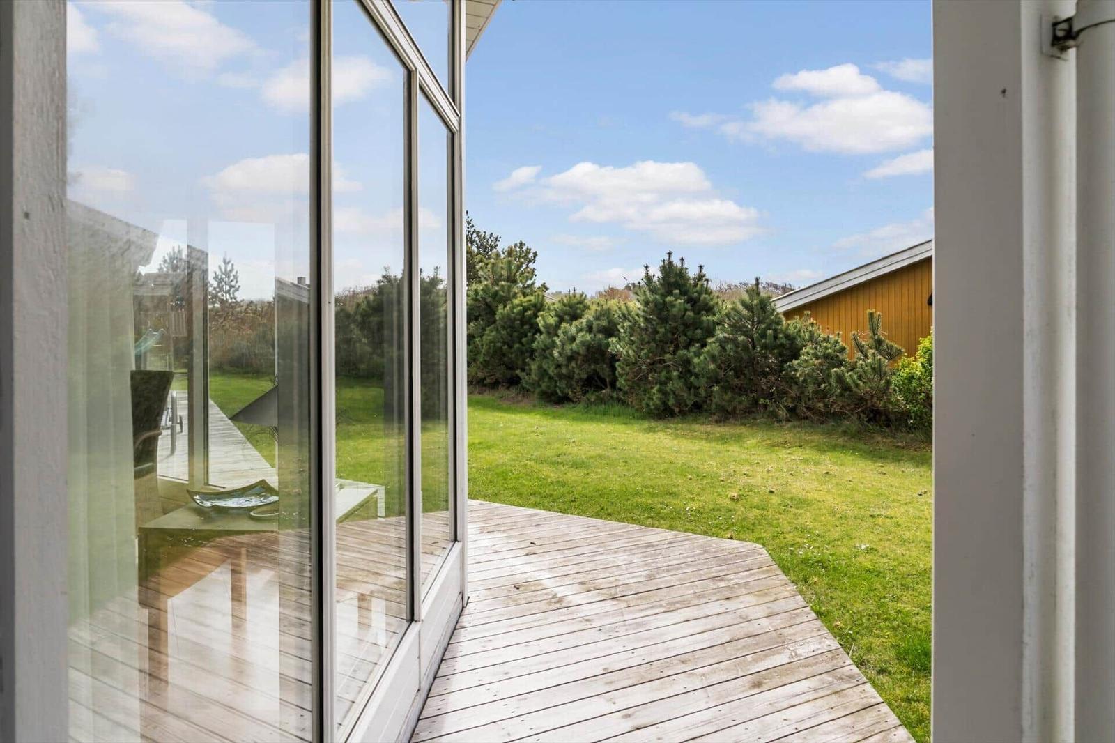 Terrasse mit Holzboden und Blick auf grünen Rasen und Bäume.
