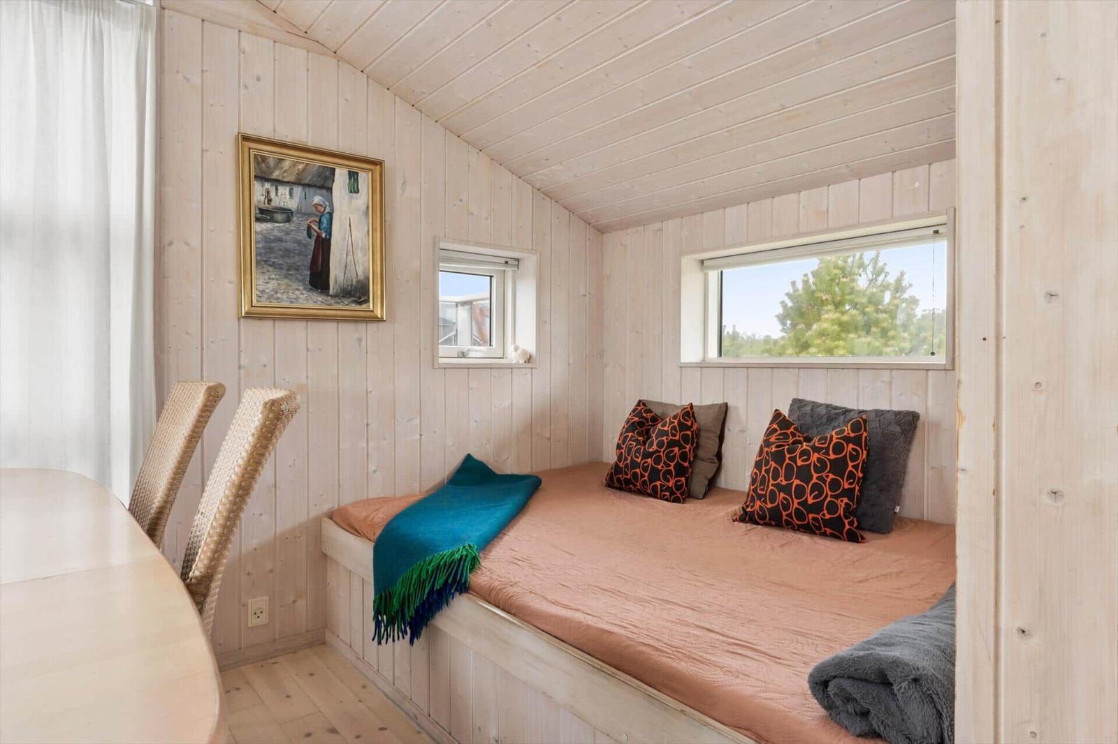 Ein Raum mit Holzwänden, einem Bett mit Kissen und einem Fenster.