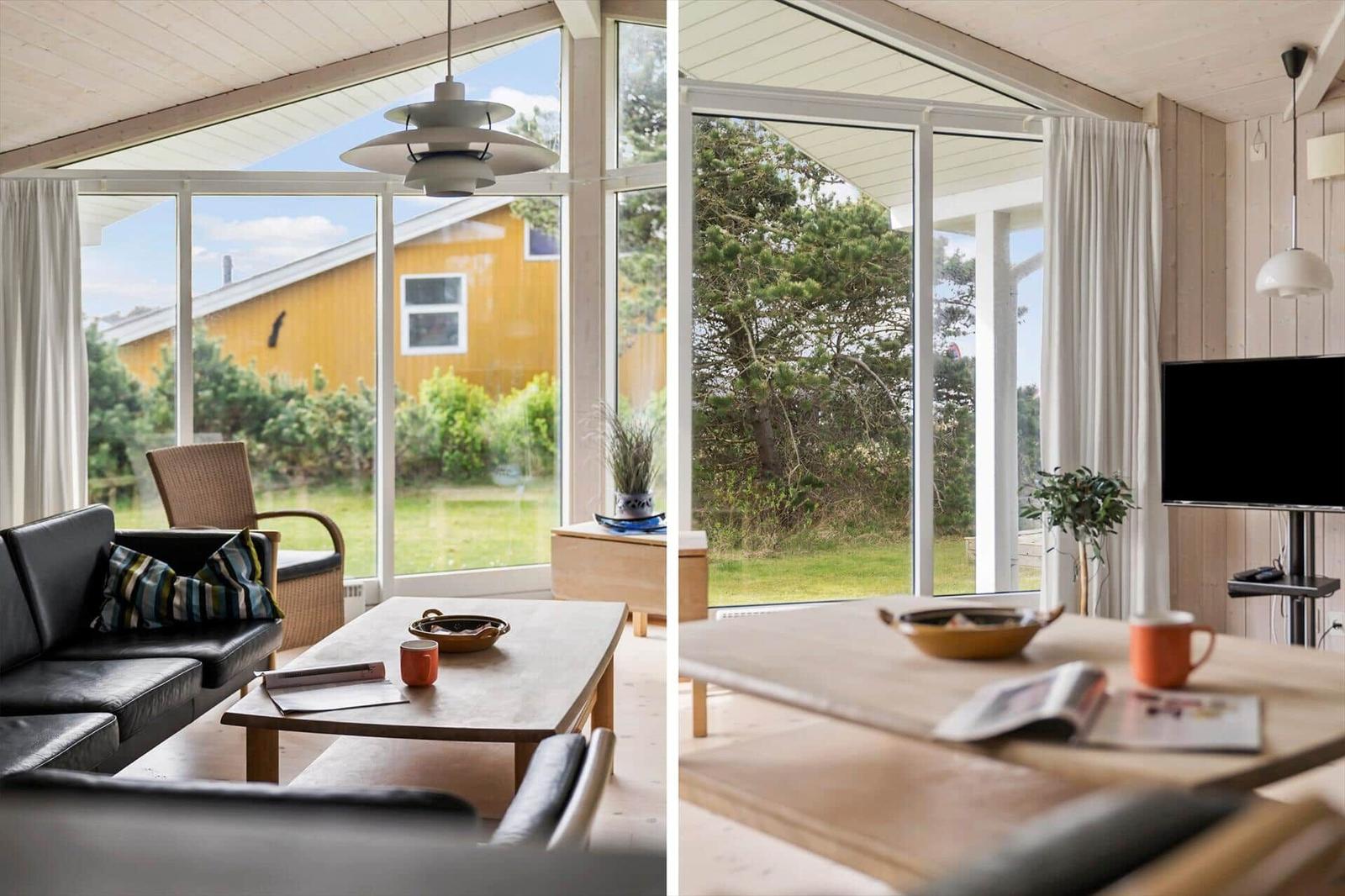 Wohnzimmer mit großem Fenster, Sofa, Tisch und Fernseher. Blick auf Garten und Baum.
