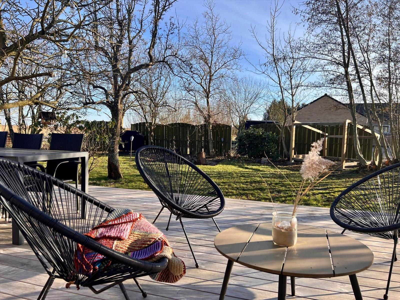 Terrasse mit Sitzgelegenheiten und Blick auf den Garten mit Bäumen.