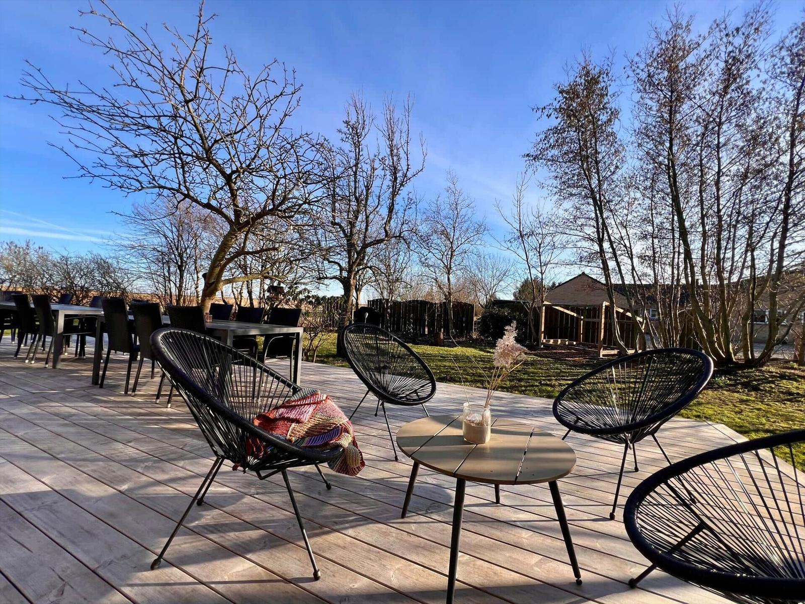 Terrasse mit Sitzgelegenheiten und Blick auf einen Garten mit Bäumen.