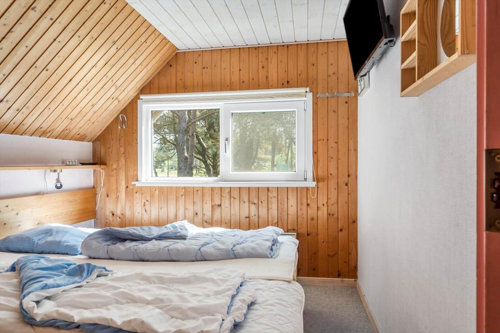 Schlafzimmer mit Holzwand, Fenster und Bett