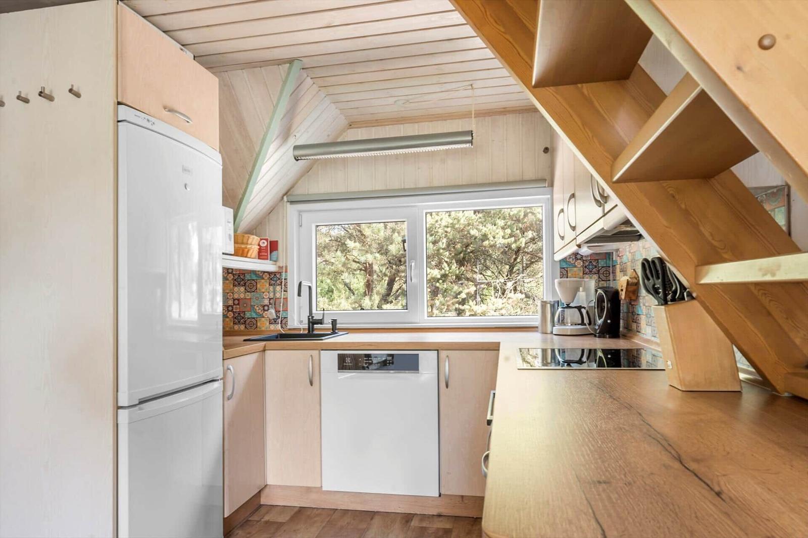 Küche mit Holzoberflächen, Fenster, Kühlschrank und Spüle.