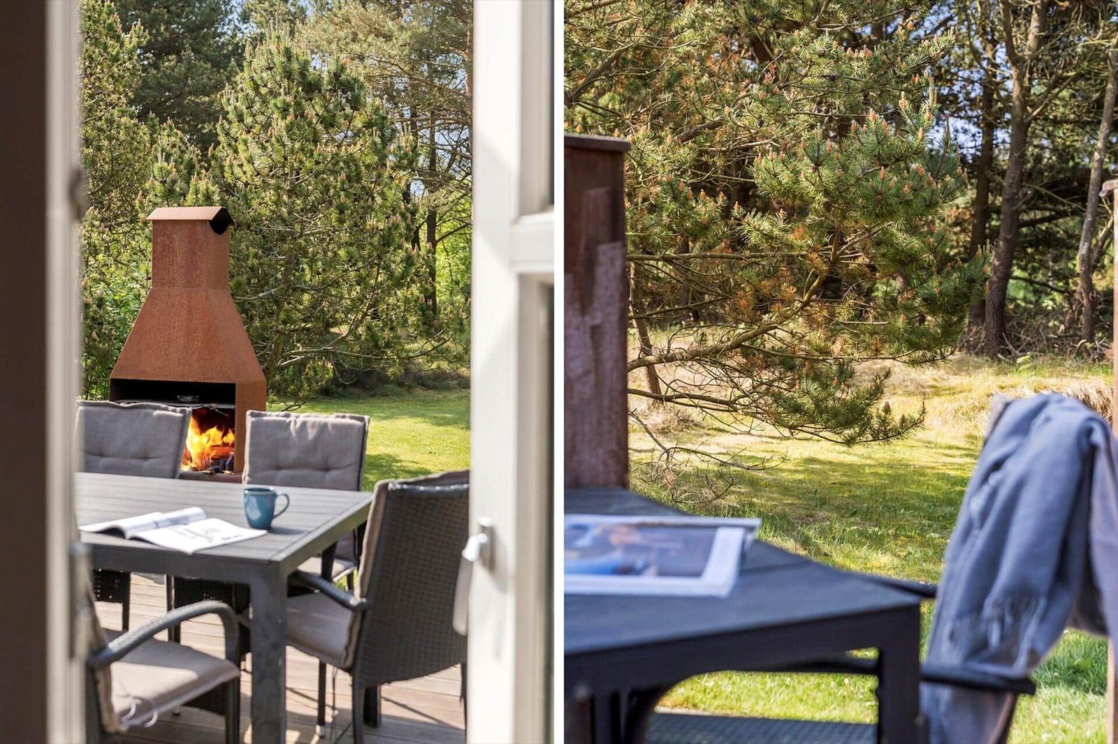 Terrasse mit Tisch, Stühlen und Kaminofen. Hintergrund: grüner Wald.